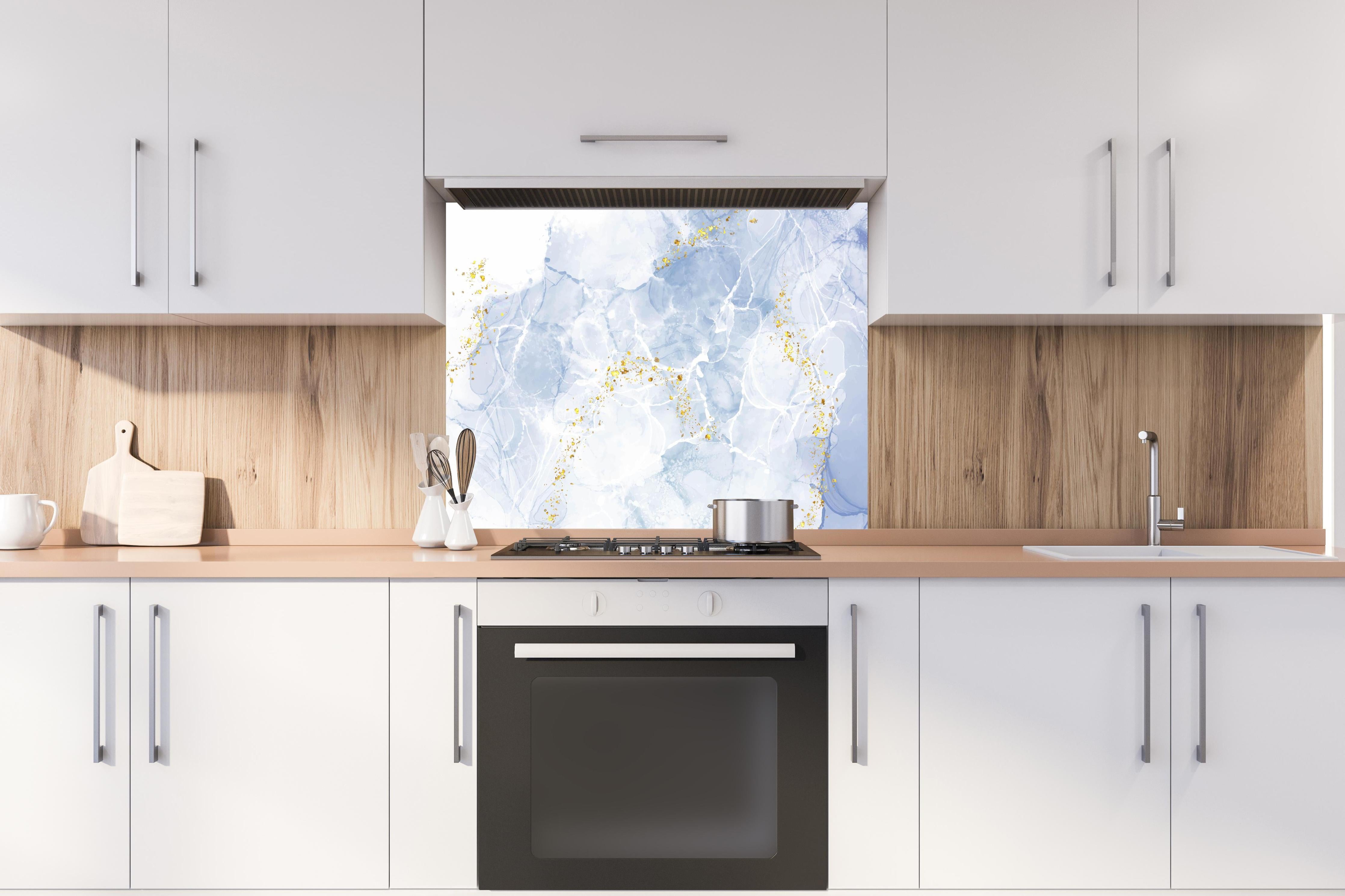Spritzschutz - Blau-Weiß-Marmor mit goldener Textur hinter einem Cerankochfeld zwischen Holz-Kochutensilien
