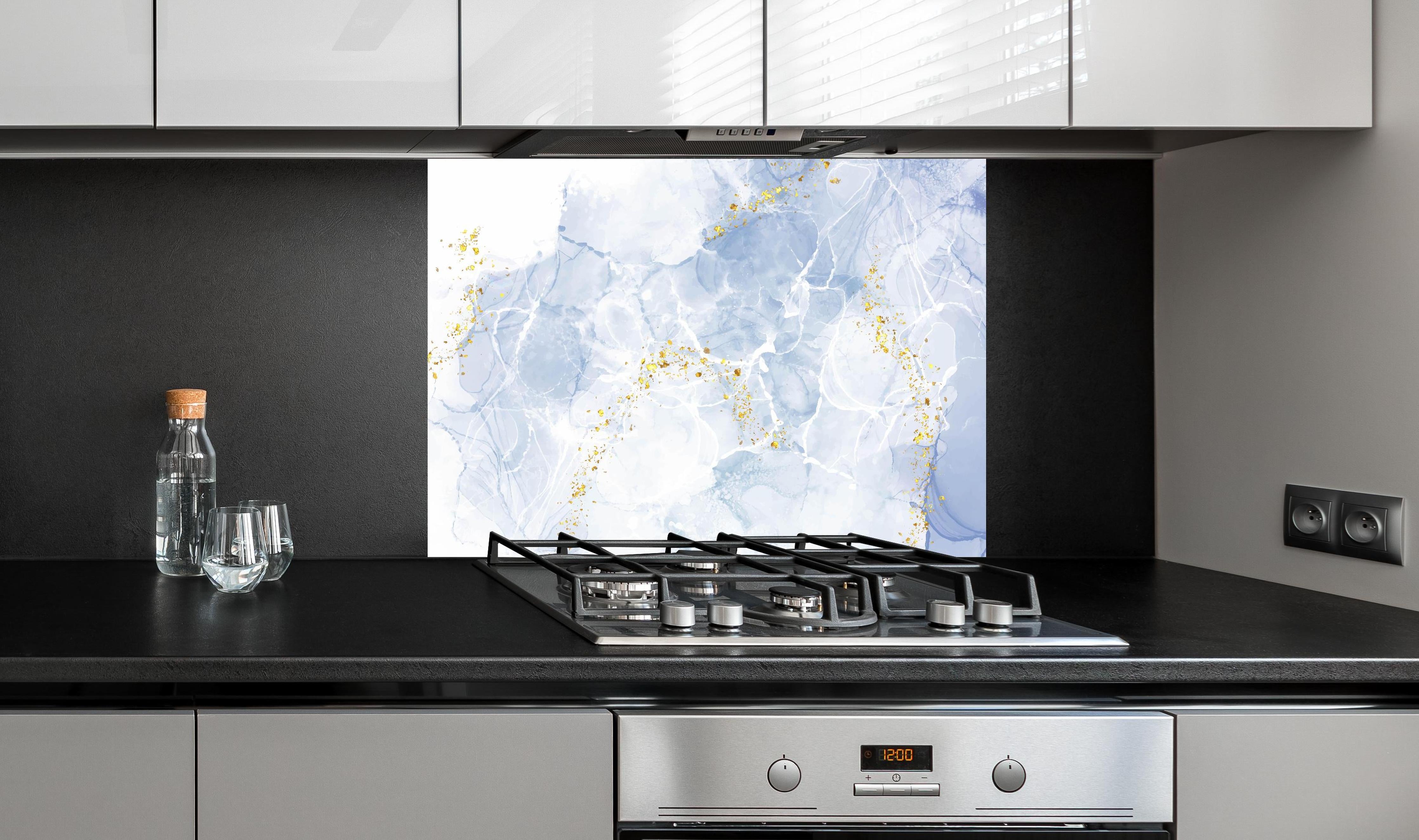 Spritzschutz - Blau-Weiß-Marmor mit goldener Textur hinter einem Cerankochfeld zwischen Holz-Kochutensilien
