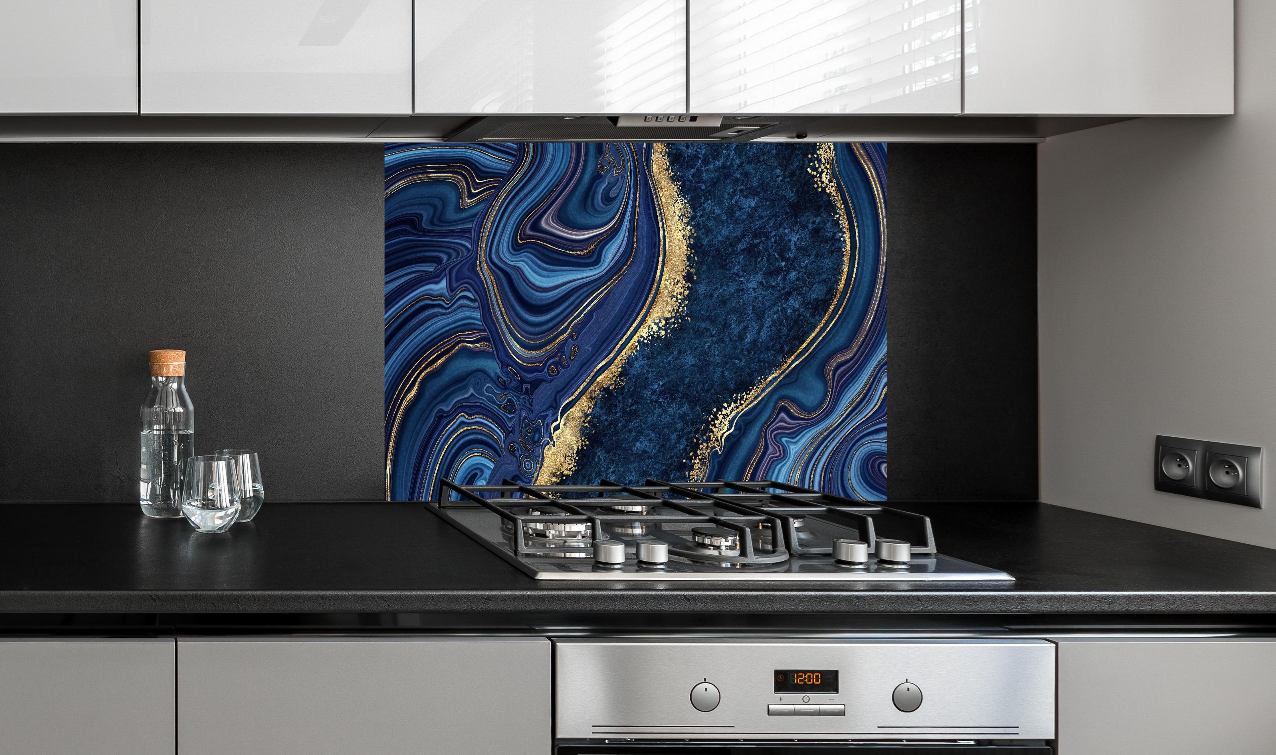 Spritzschutz - Blau goldenes Mosaik Design aus Marmor hinter einem Cerankochfeld zwischen Holz-Kochutensilien
