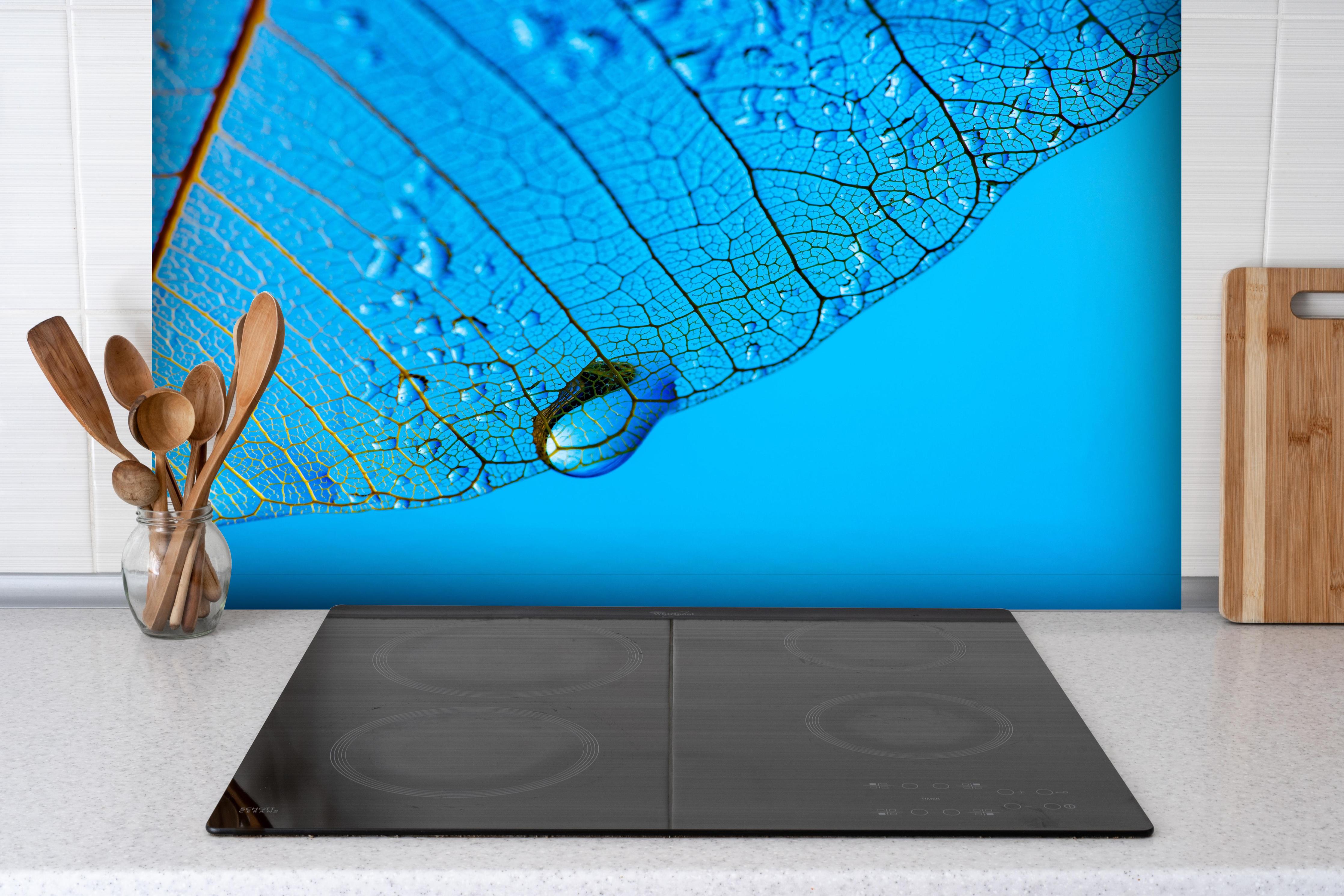 Spritzschutz - Blaue Blattstruktur mit Tautropfen Makro hinter einem Cerankochfeld zwischen Holz-Kochutensilien
