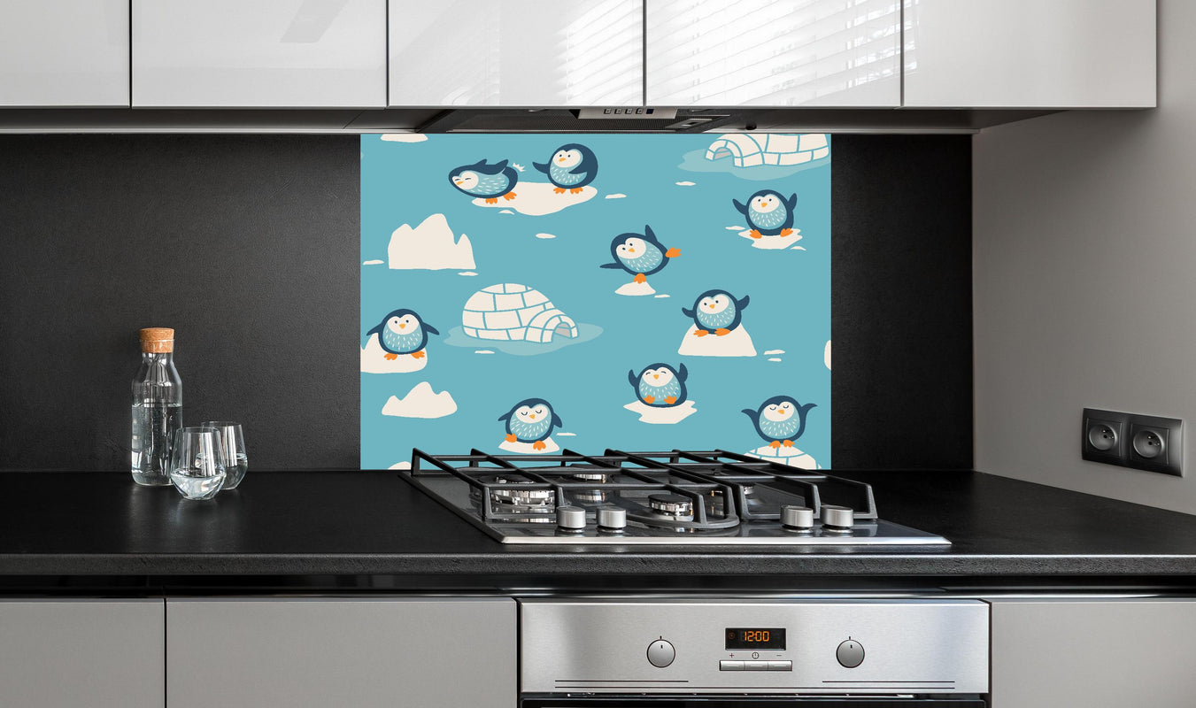 Spritzschutz - Blaue Pinguin Illustration Kindermuster hinter einem Cerankochfeld zwischen Holz-Kochutensilien
