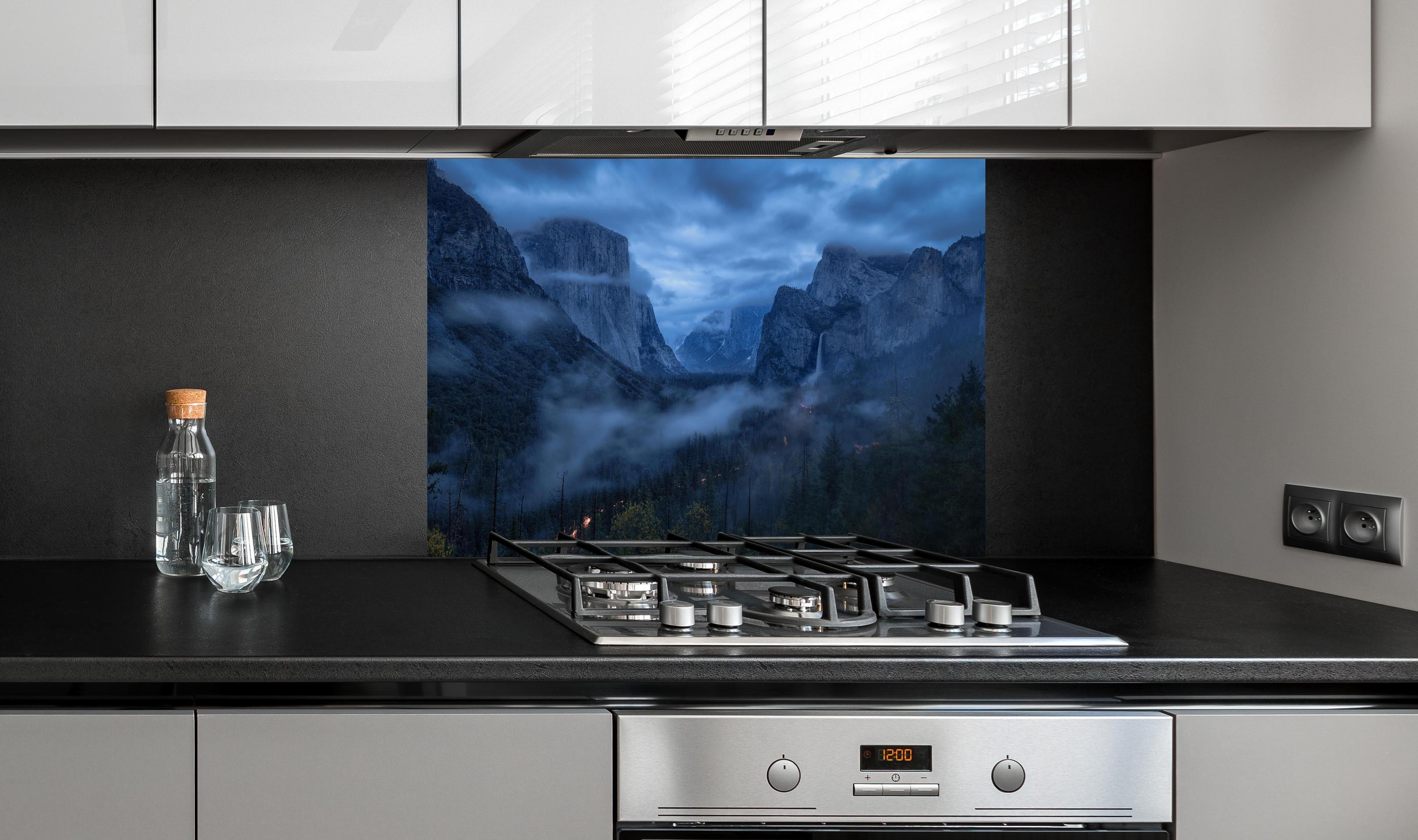 Spritzschutz - Blaustichige Dämmerung im nebelverhangenen Yosemite hinter einem Cerankochfeld zwischen Holz-Kochutensilien
