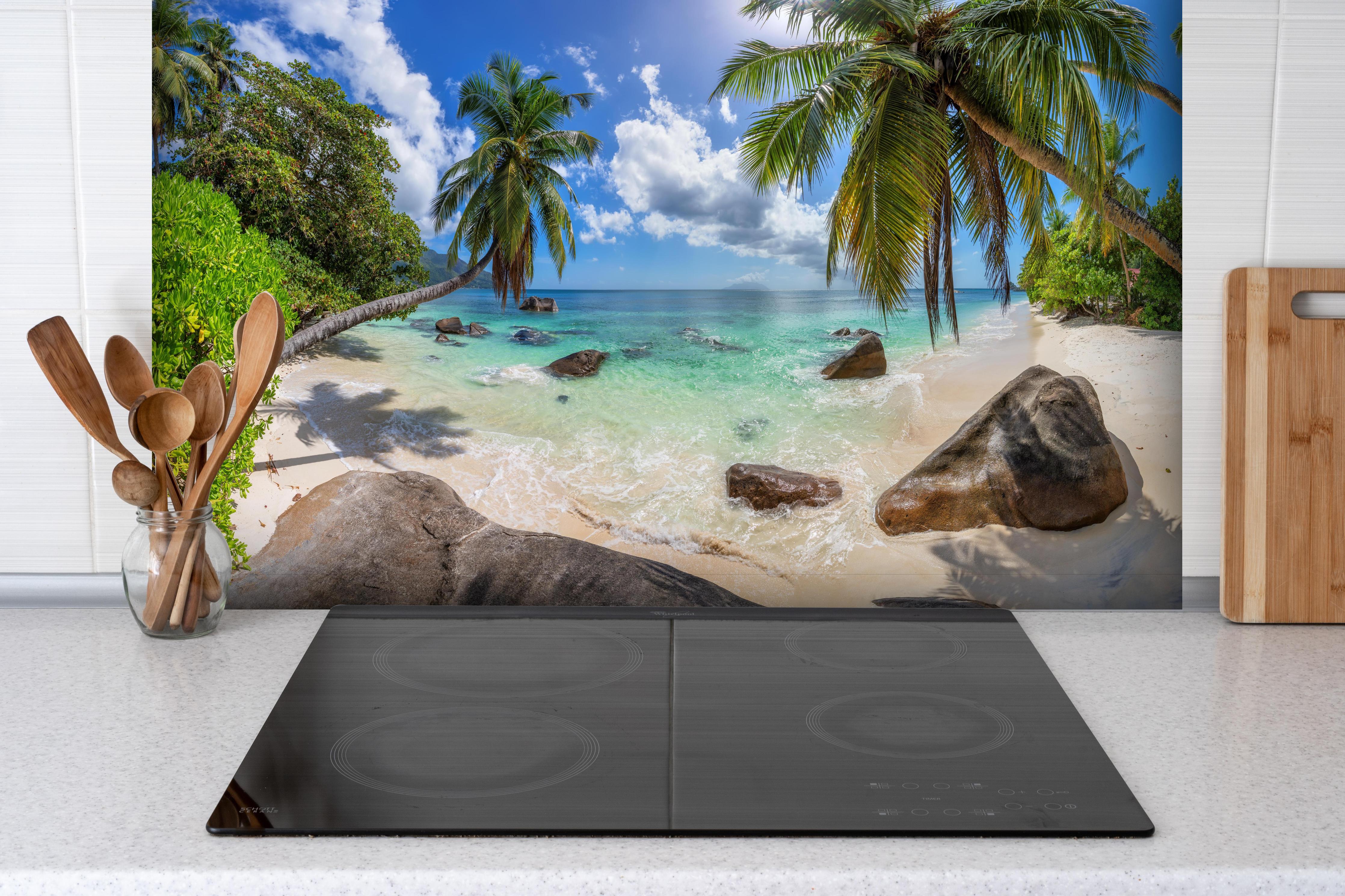 Spritzschutz - Blick auf den schönen tropischen Strand hinter einem Cerankochfeld zwischen Holz-Kochutensilien
