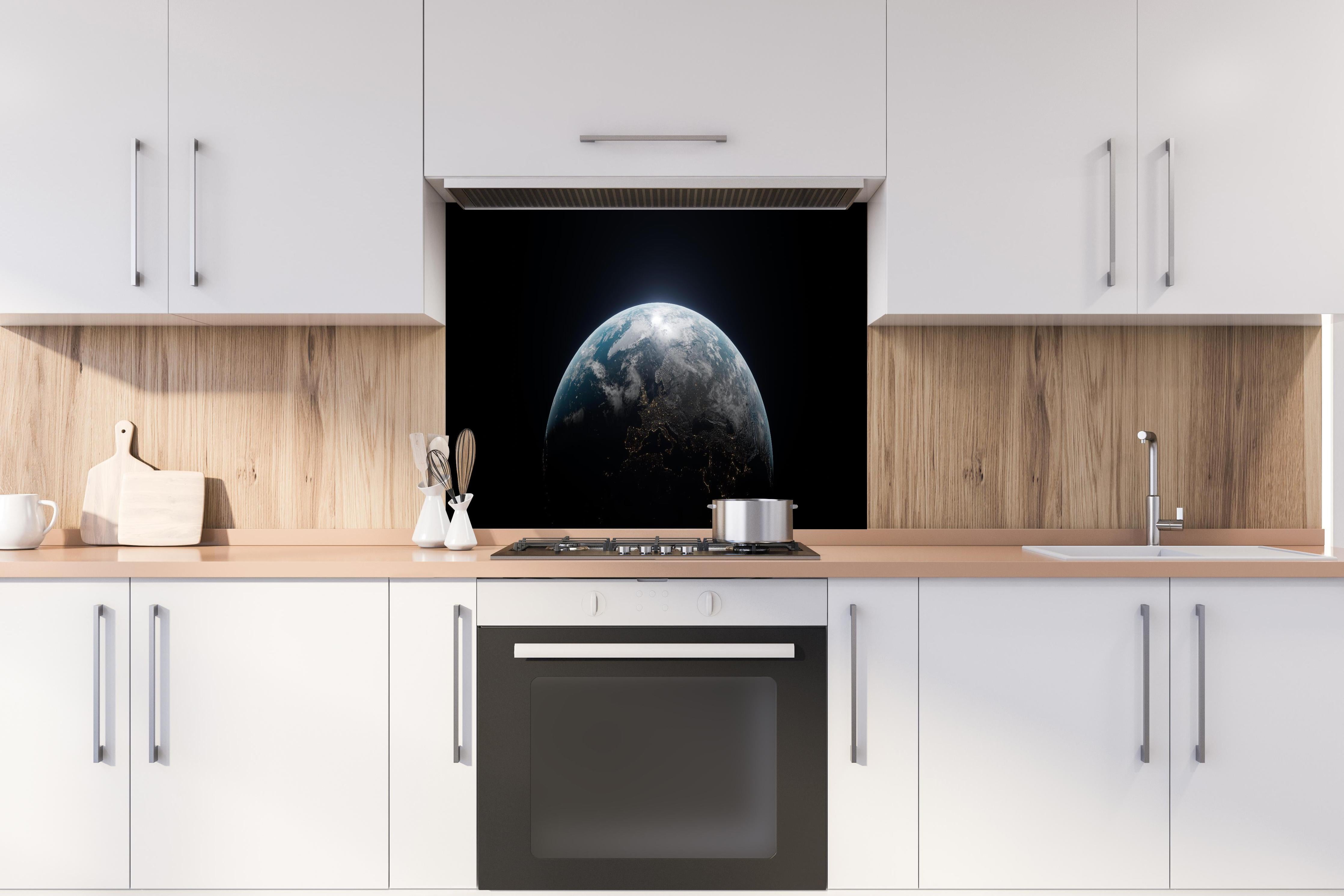 Spritzschutz - Blick auf die Erde hinter einem Cerankochfeld zwischen Holz-Kochutensilien
