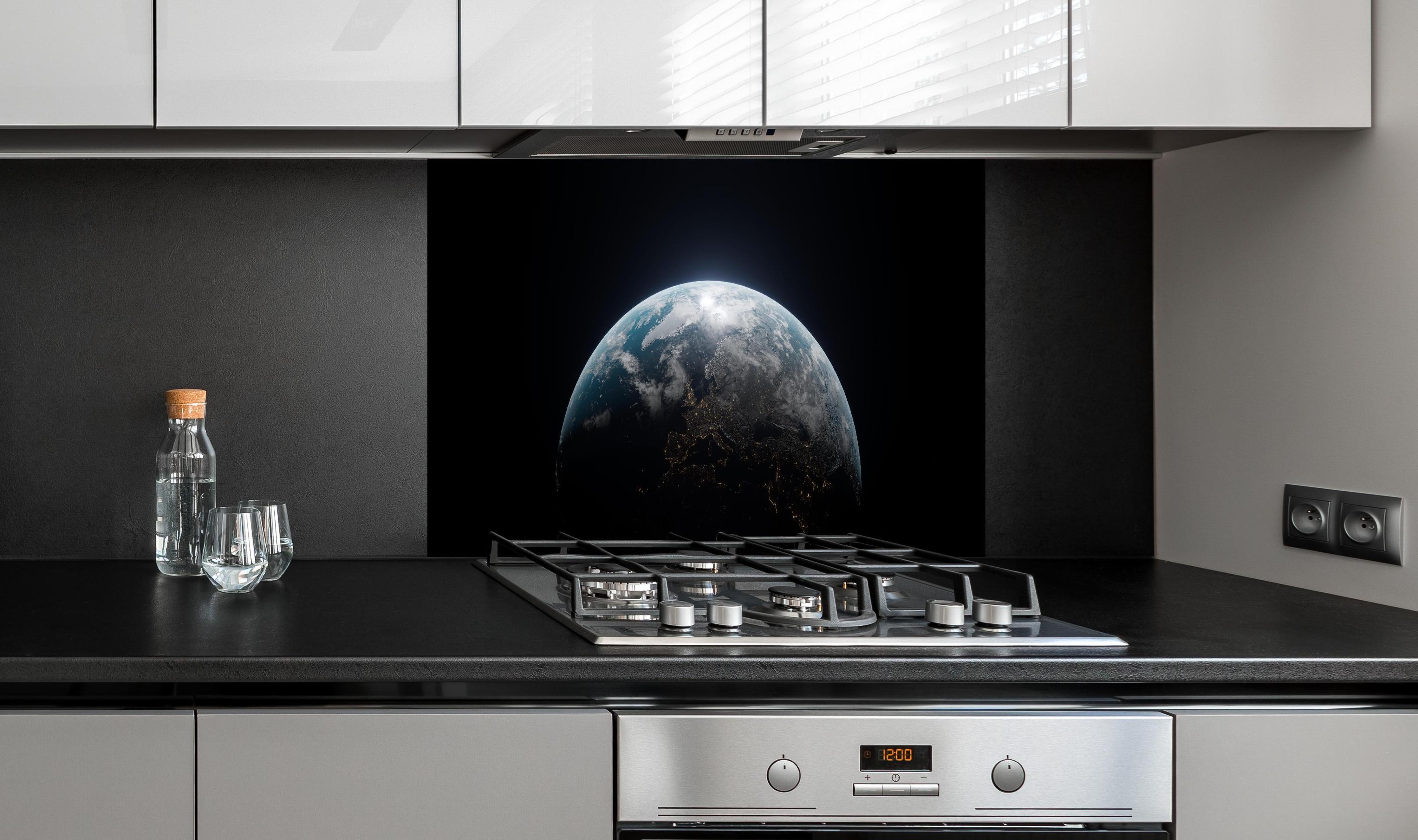 Spritzschutz - Blick auf die Erde hinter einem Cerankochfeld zwischen Holz-Kochutensilien
