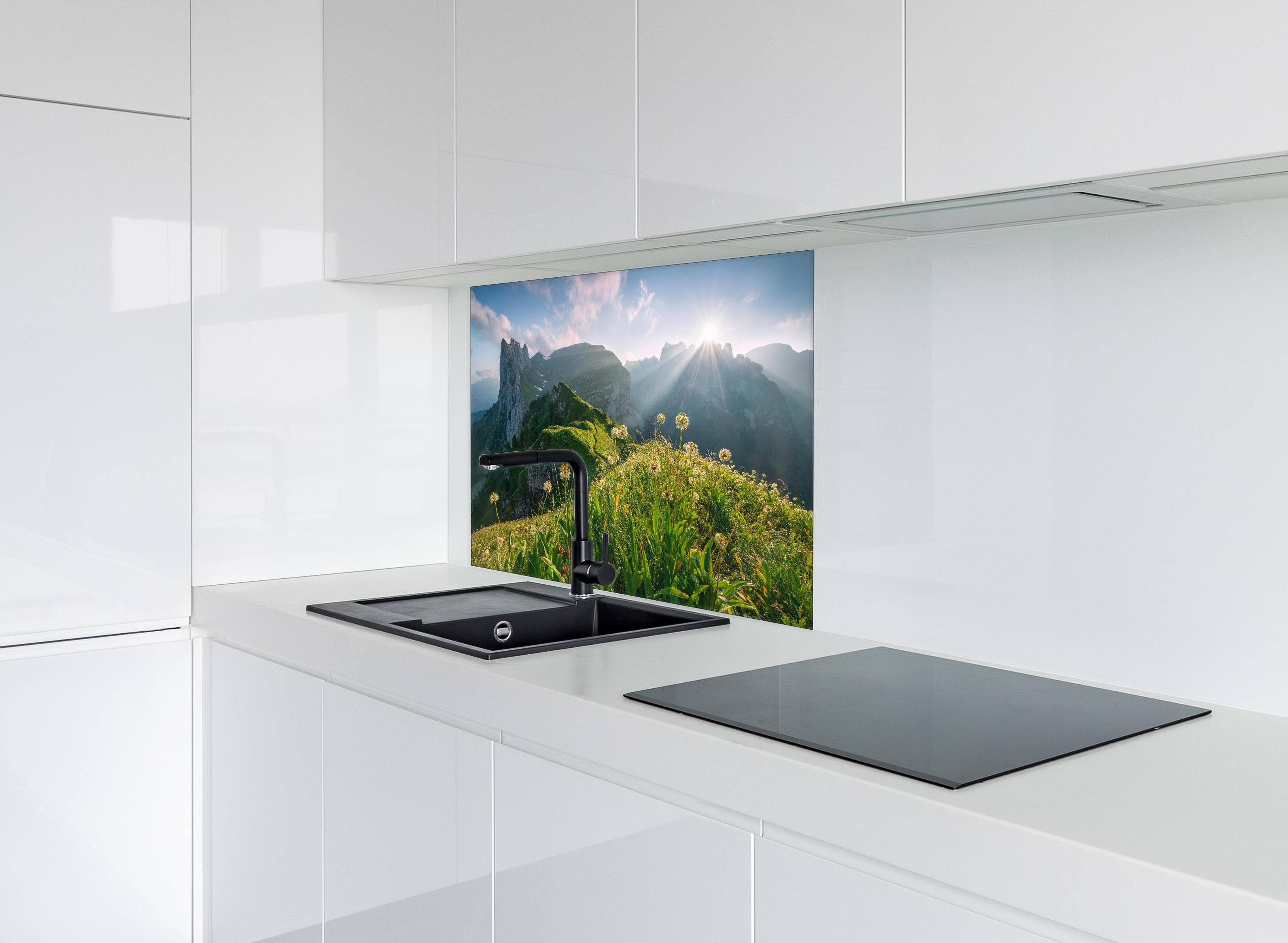 Spritzschutz - Blühende Alpenwiesen bei Sonnenaufgang hinter einem Cerankochfeld zwischen Holz-Kochutensilien
