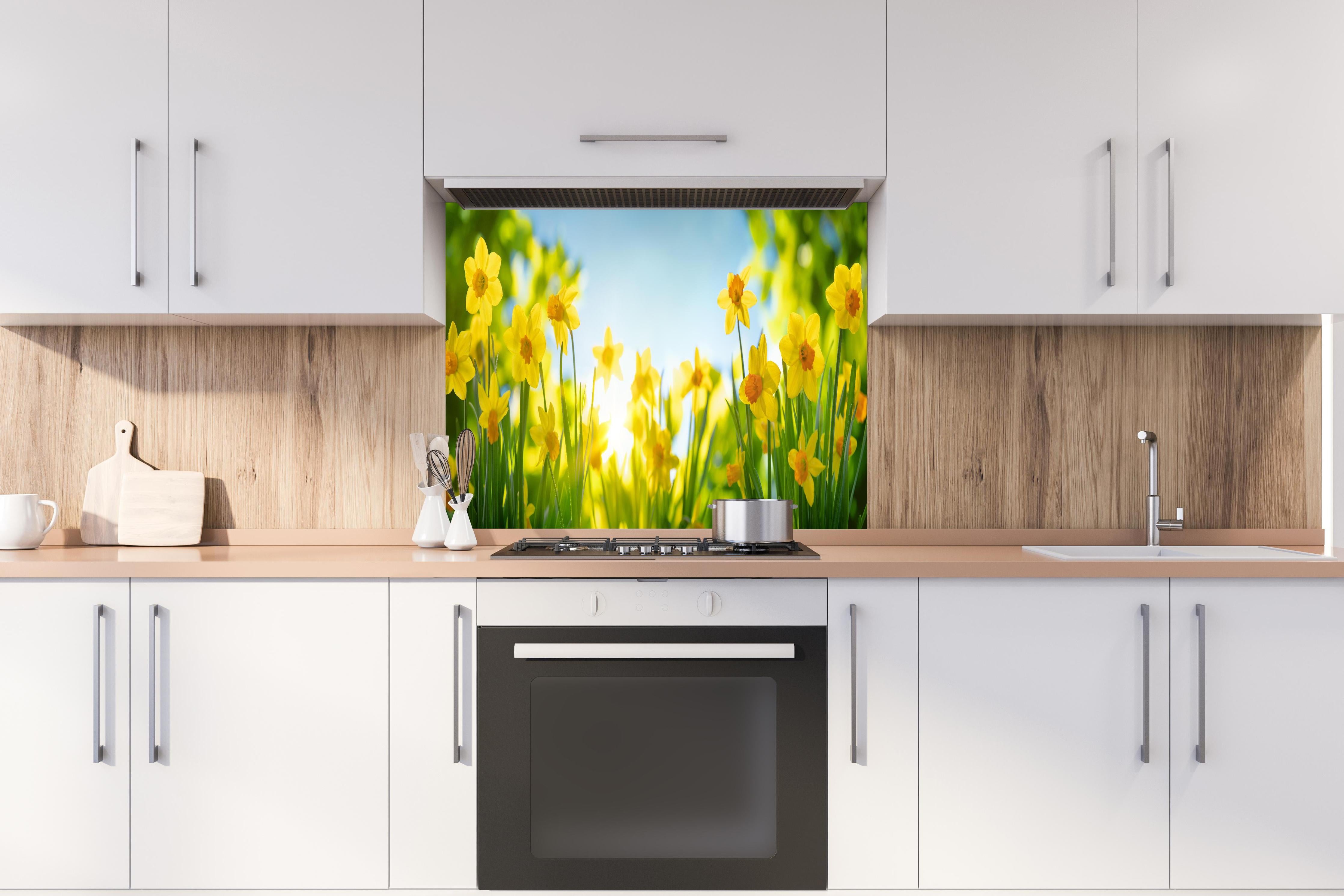 Spritzschutz - Blühende Frühlings-Narzissen hinter einem Cerankochfeld zwischen Holz-Kochutensilien
