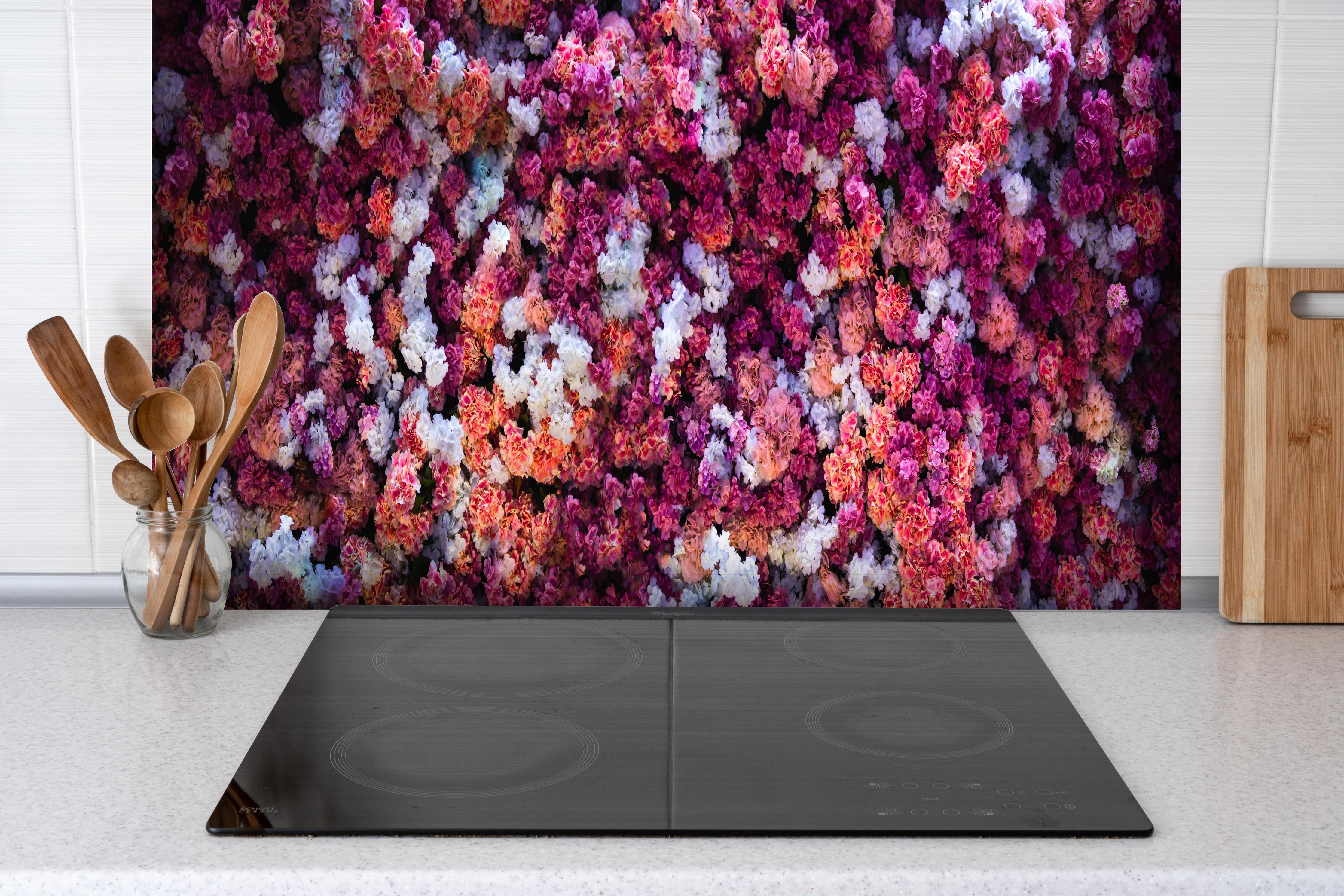 Spritzschutz - Blumenwand in Rot und Weiß Naturhintergrund hinter einem Cerankochfeld zwischen Holz-Kochutensilien
