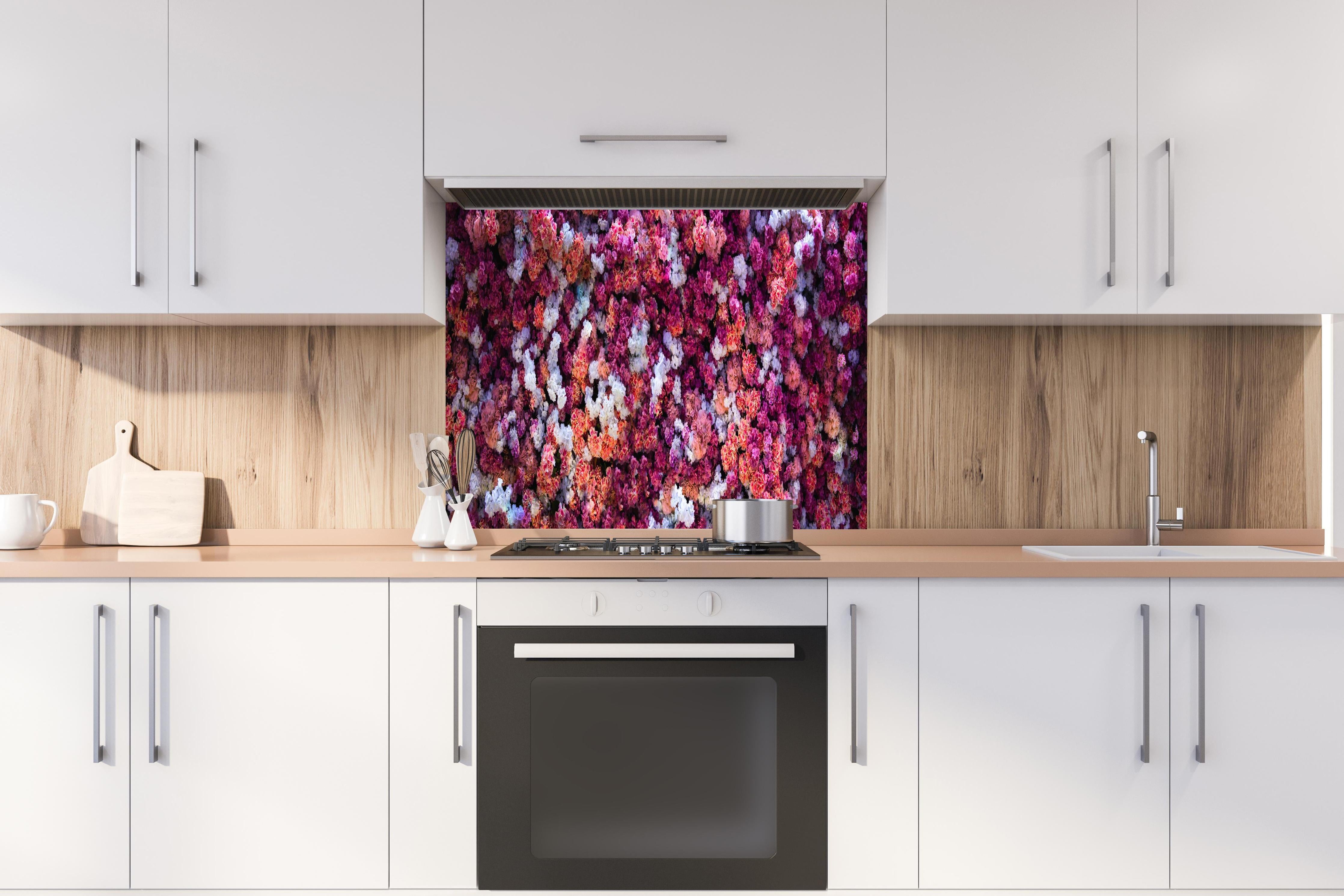 Spritzschutz - Blumenwand in Rot und Weiß Naturhintergrund hinter einem Cerankochfeld zwischen Holz-Kochutensilien
