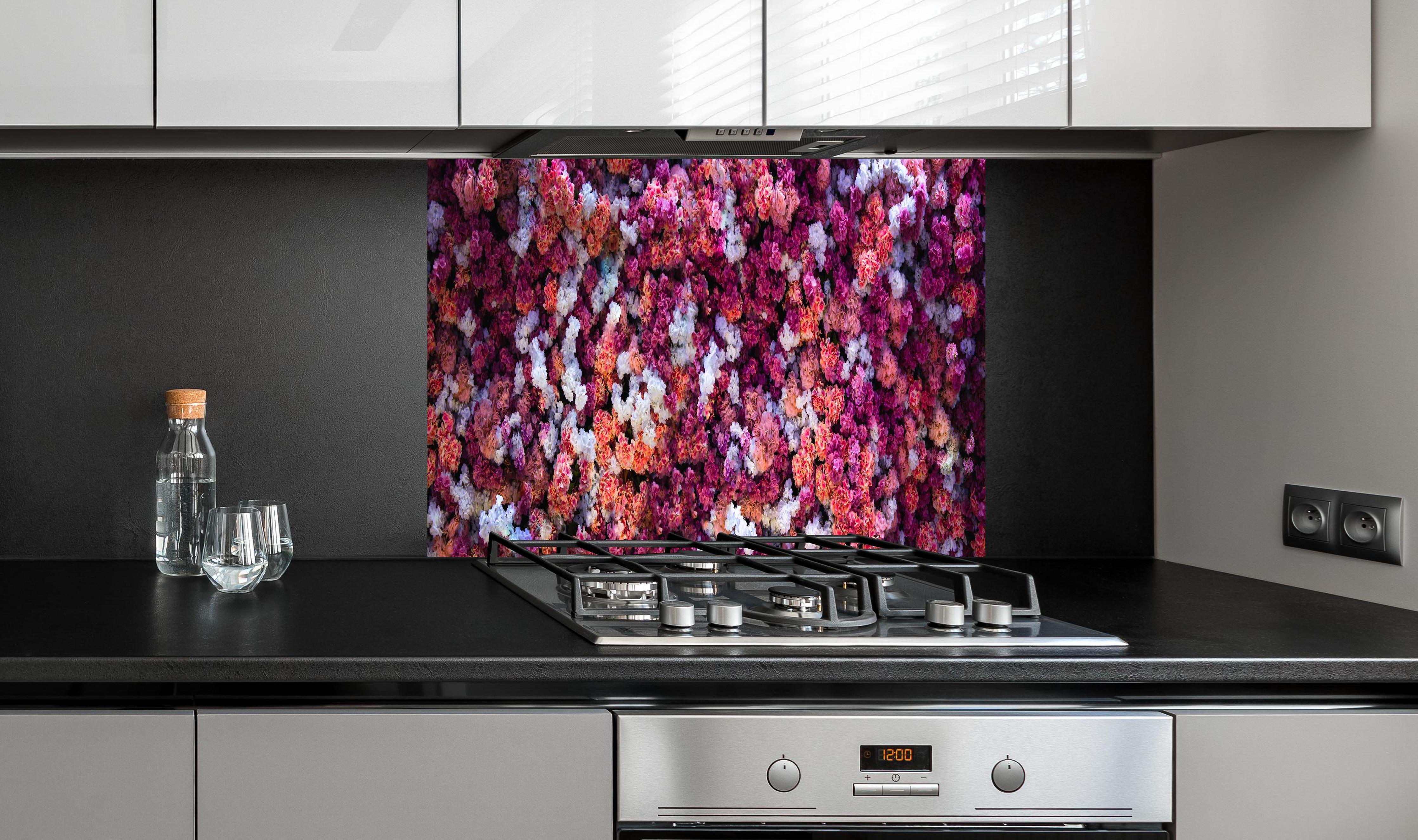 Spritzschutz - Blumenwand in Rot und Weiß Naturhintergrund hinter einem Cerankochfeld zwischen Holz-Kochutensilien
