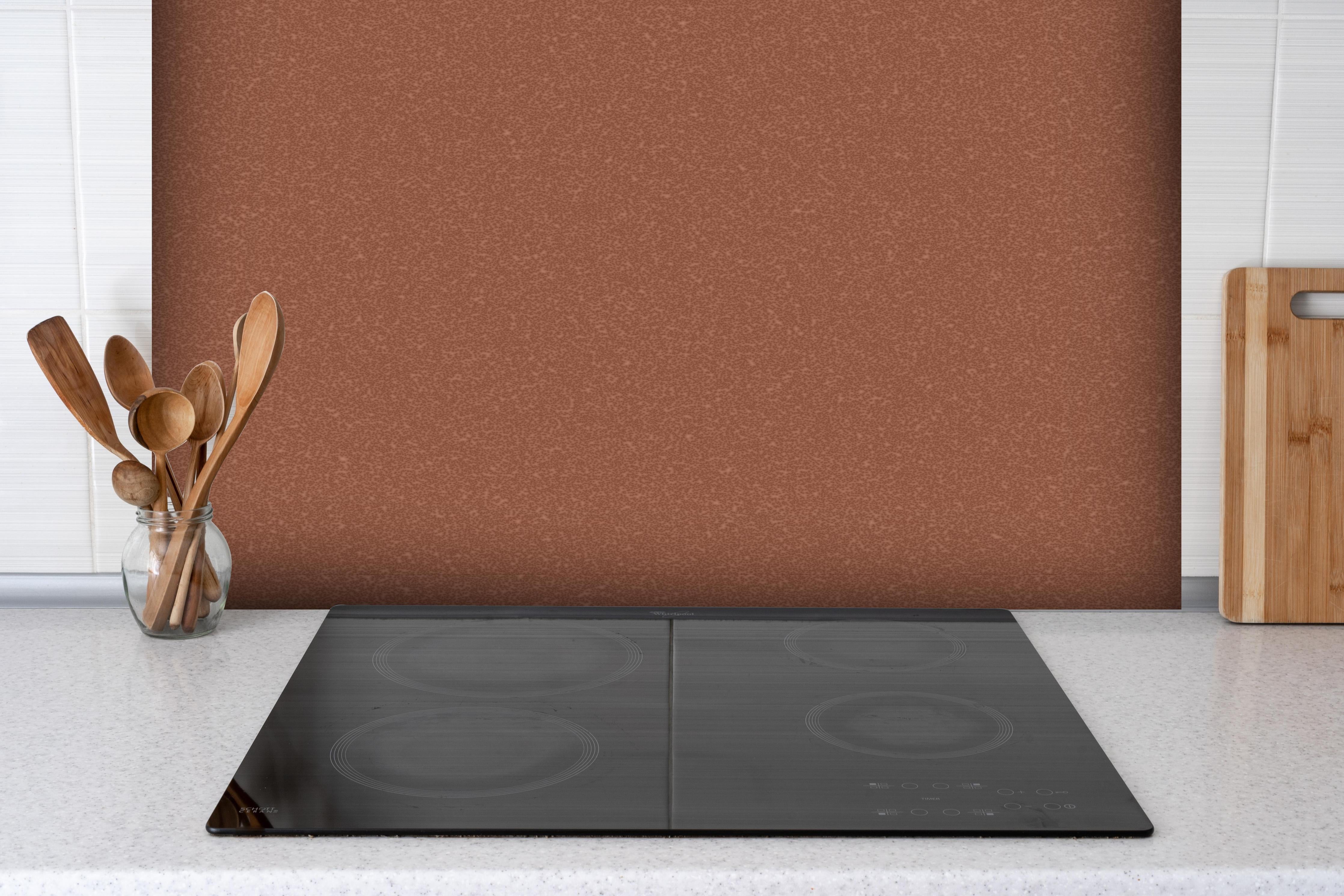 Spritzschutz - Bräunlicher Hintergrund - Zimtfarbe hinter einem Cerankochfeld zwischen Holz-Kochutensilien
