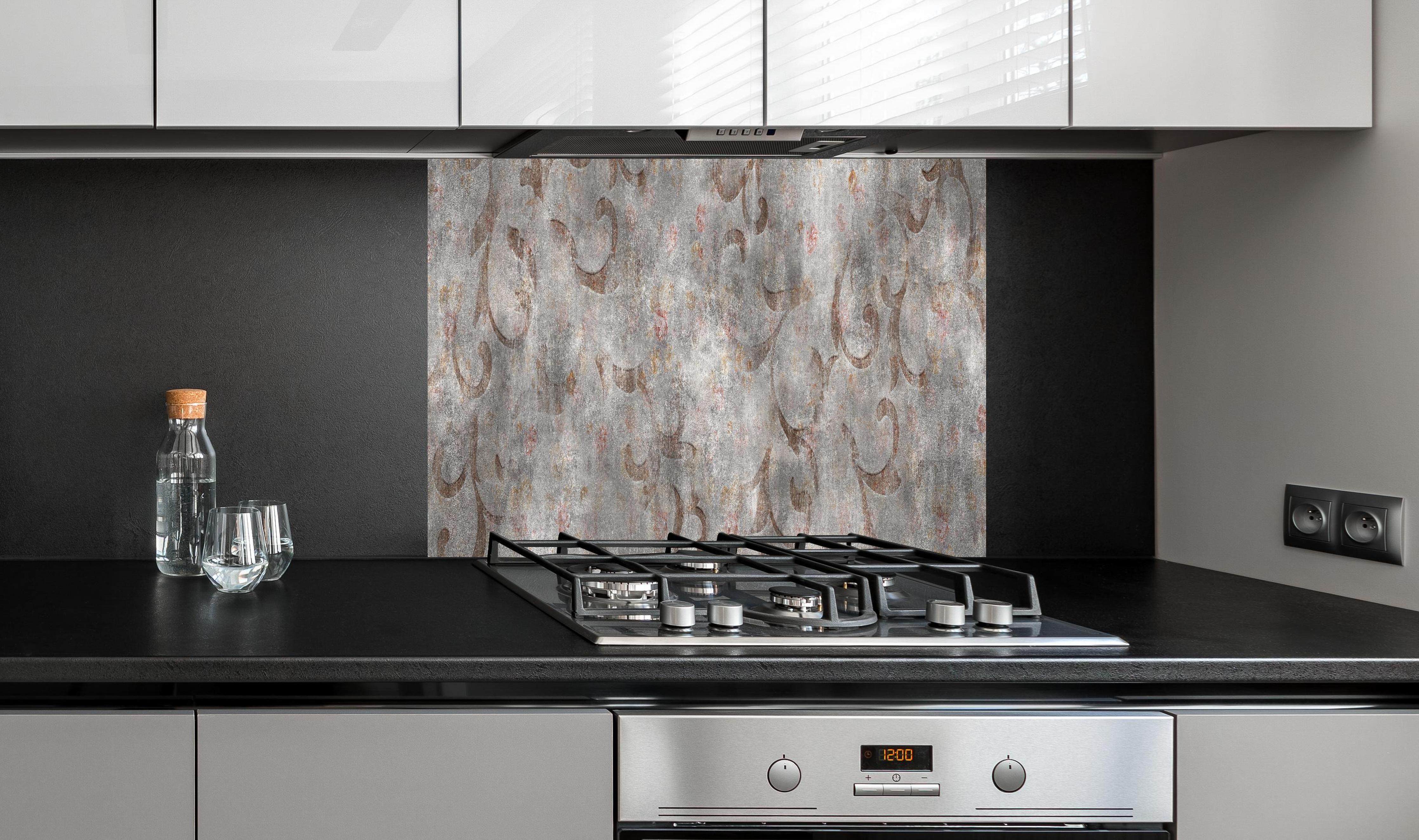 Spritzschutz - Braunes Blätter Muster auf gräulichem Zement hinter einem Cerankochfeld zwischen Holz-Kochutensilien
