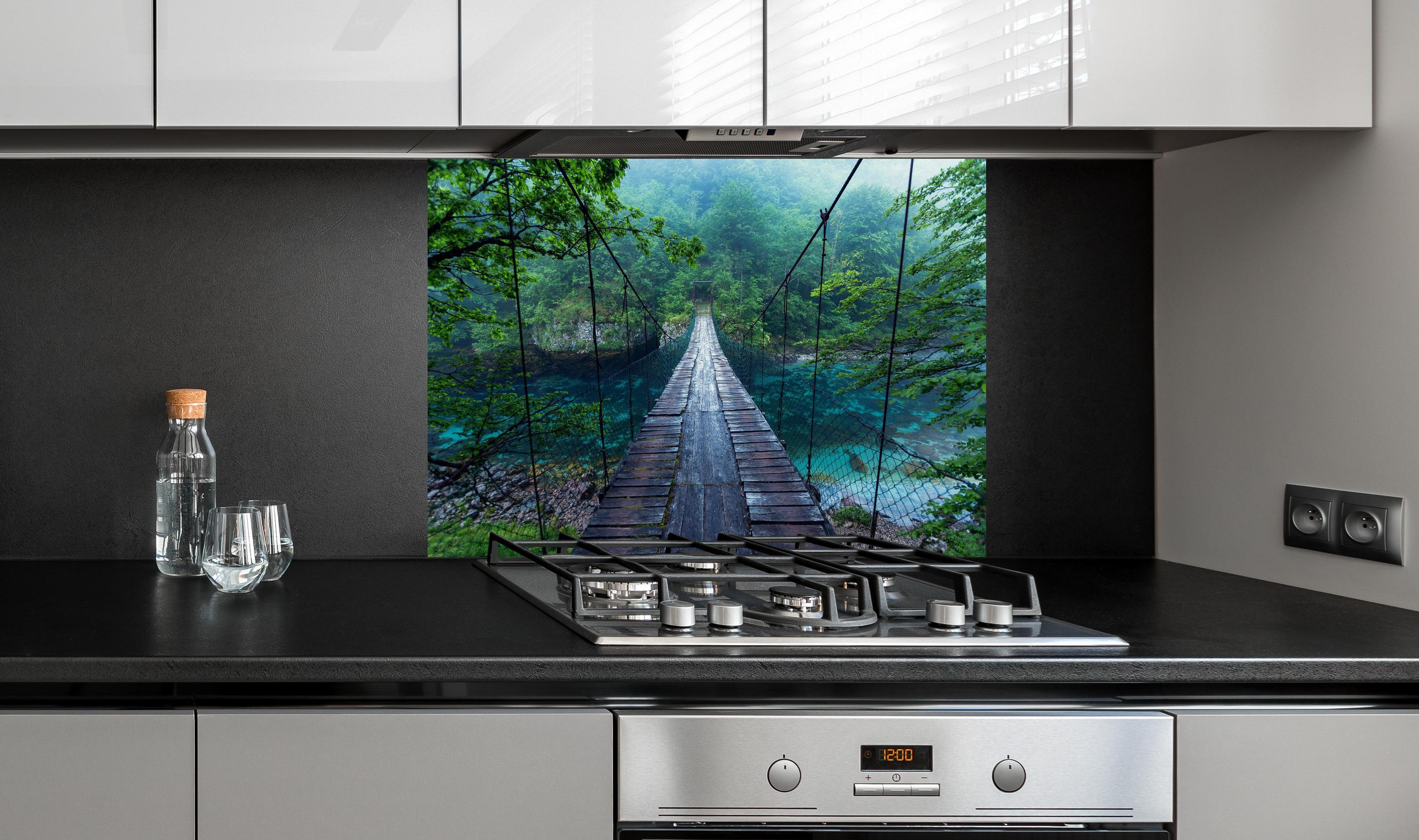 Spritzschutz - Brücke über Kristallklarem Fluss hinter einem Cerankochfeld zwischen Holz-Kochutensilien
