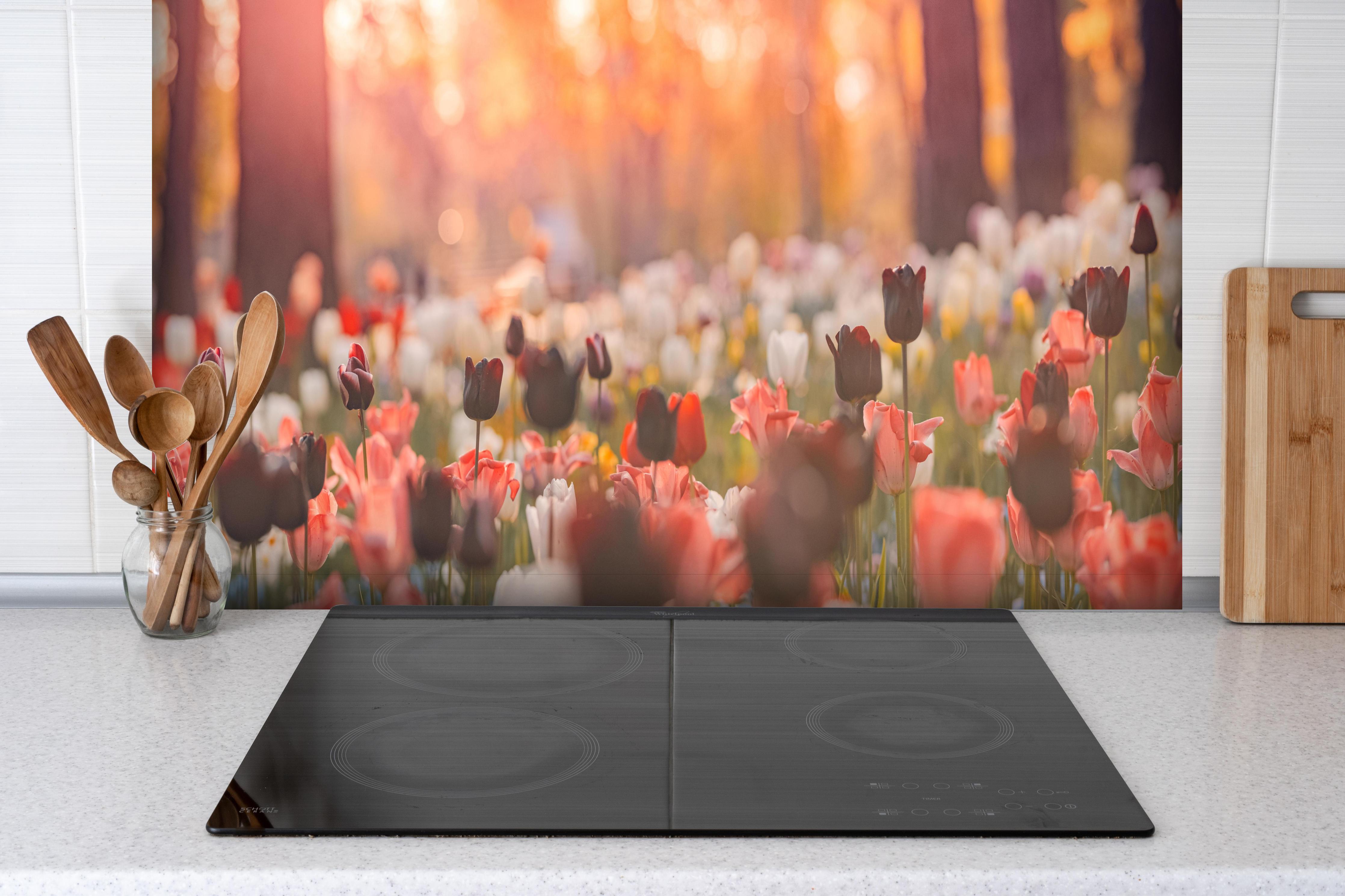 Spritzschutz - Bunte Blumenwiese mit Tulpen hinter einem Cerankochfeld zwischen Holz-Kochutensilien
