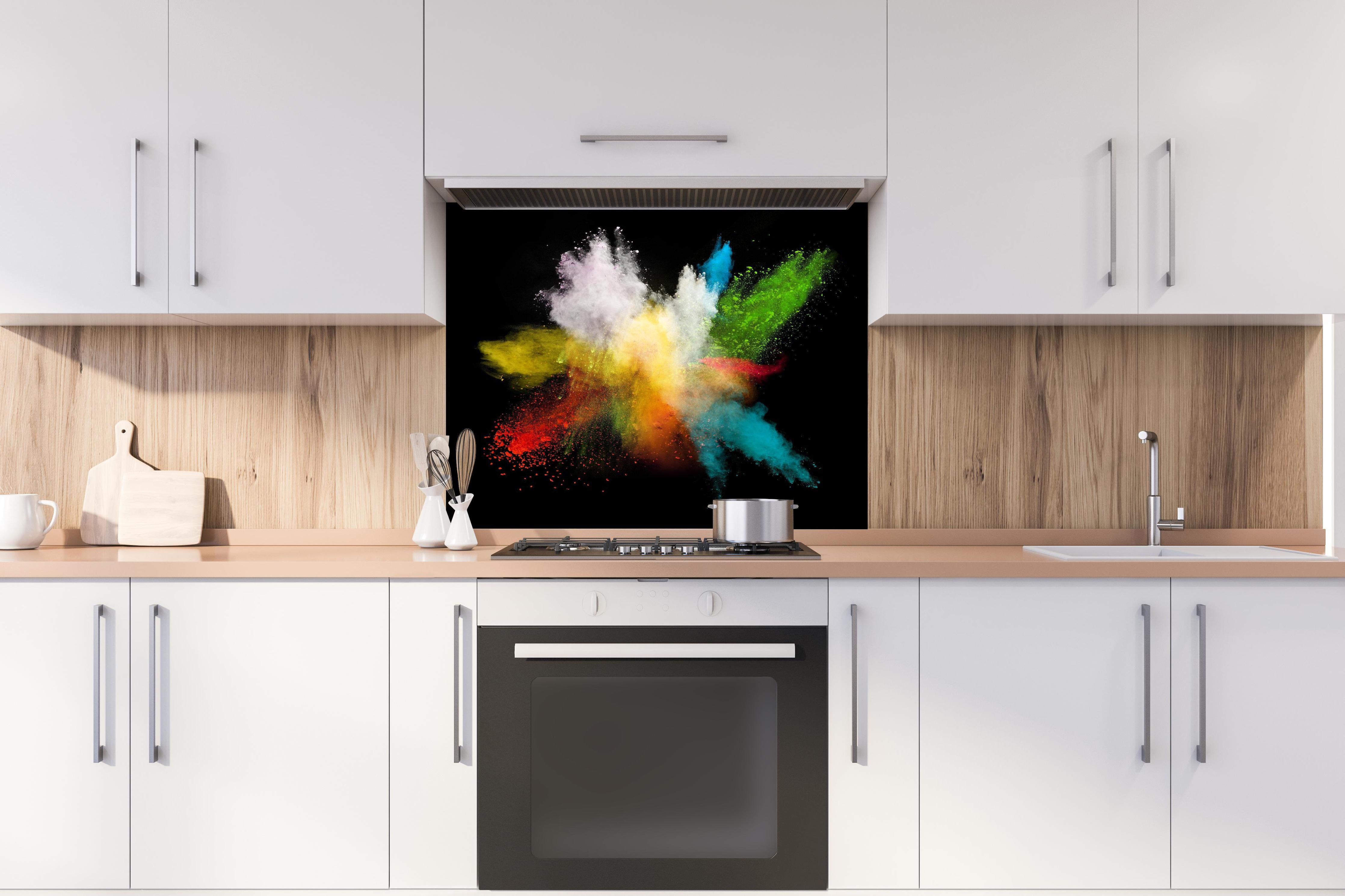 Spritzschutz - Bunte Farbexplosion auf schwarzem Hintergrund hinter einem Cerankochfeld zwischen Holz-Kochutensilien
