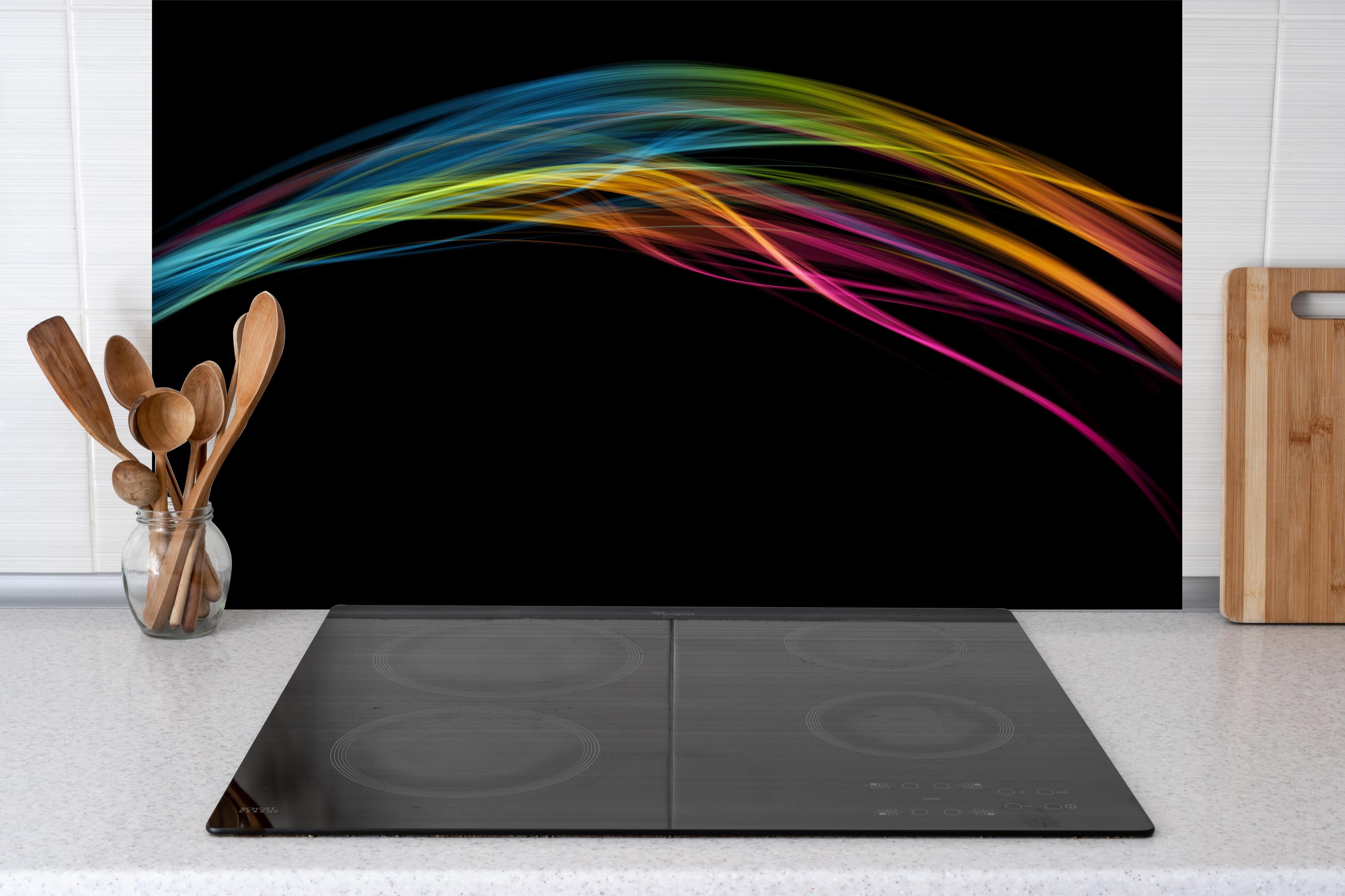 Spritzschutz - Bunte Lichtwellen auf schwarzem Hintergrund hinter einem Cerankochfeld zwischen Holz-Kochutensilien
