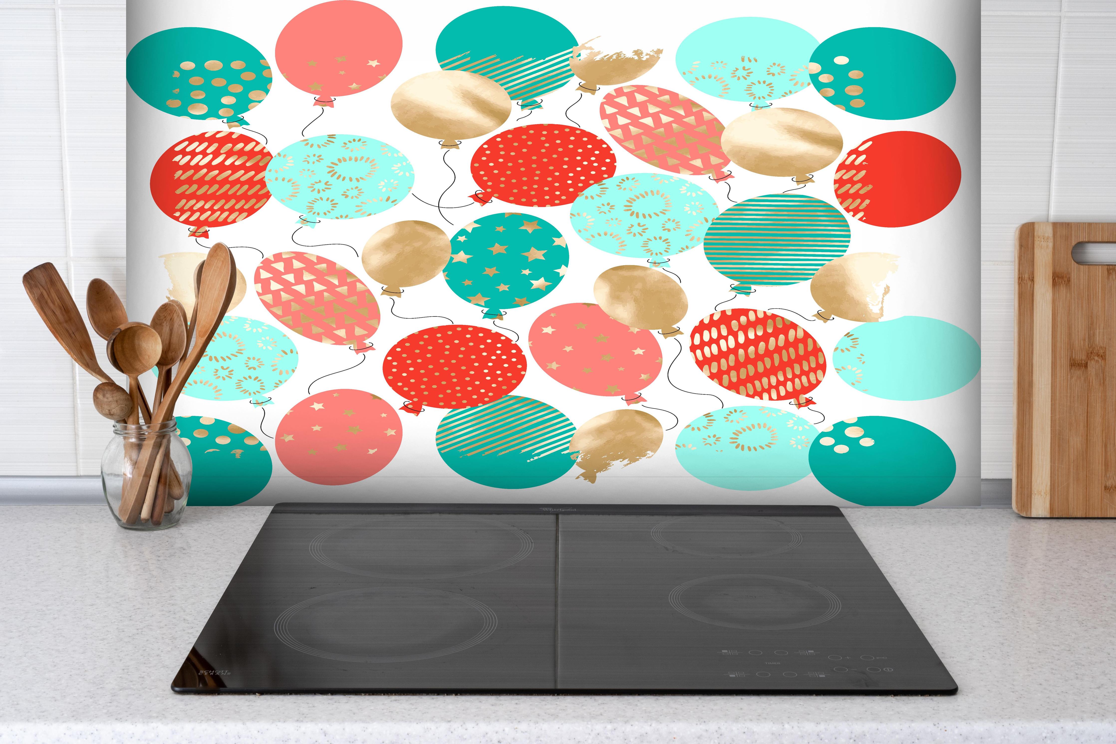 Spritzschutz - Bunte Luftballons Party-Deko Set hinter einem Cerankochfeld zwischen Holz-Kochutensilien
