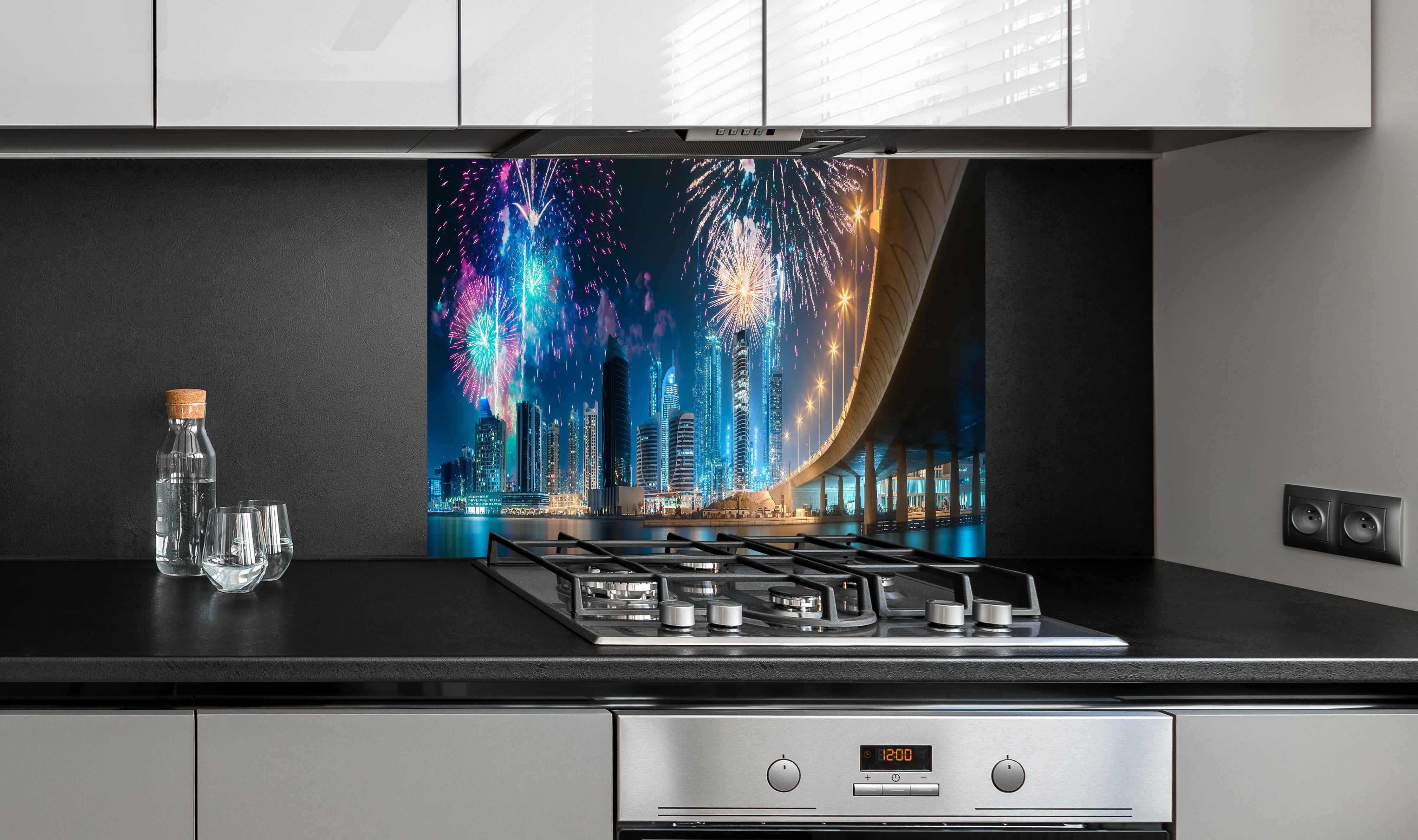 Spritzschutz - Buntes Feuerwerk über Dubai Business Bay hinter einem Cerankochfeld zwischen Holz-Kochutensilien
