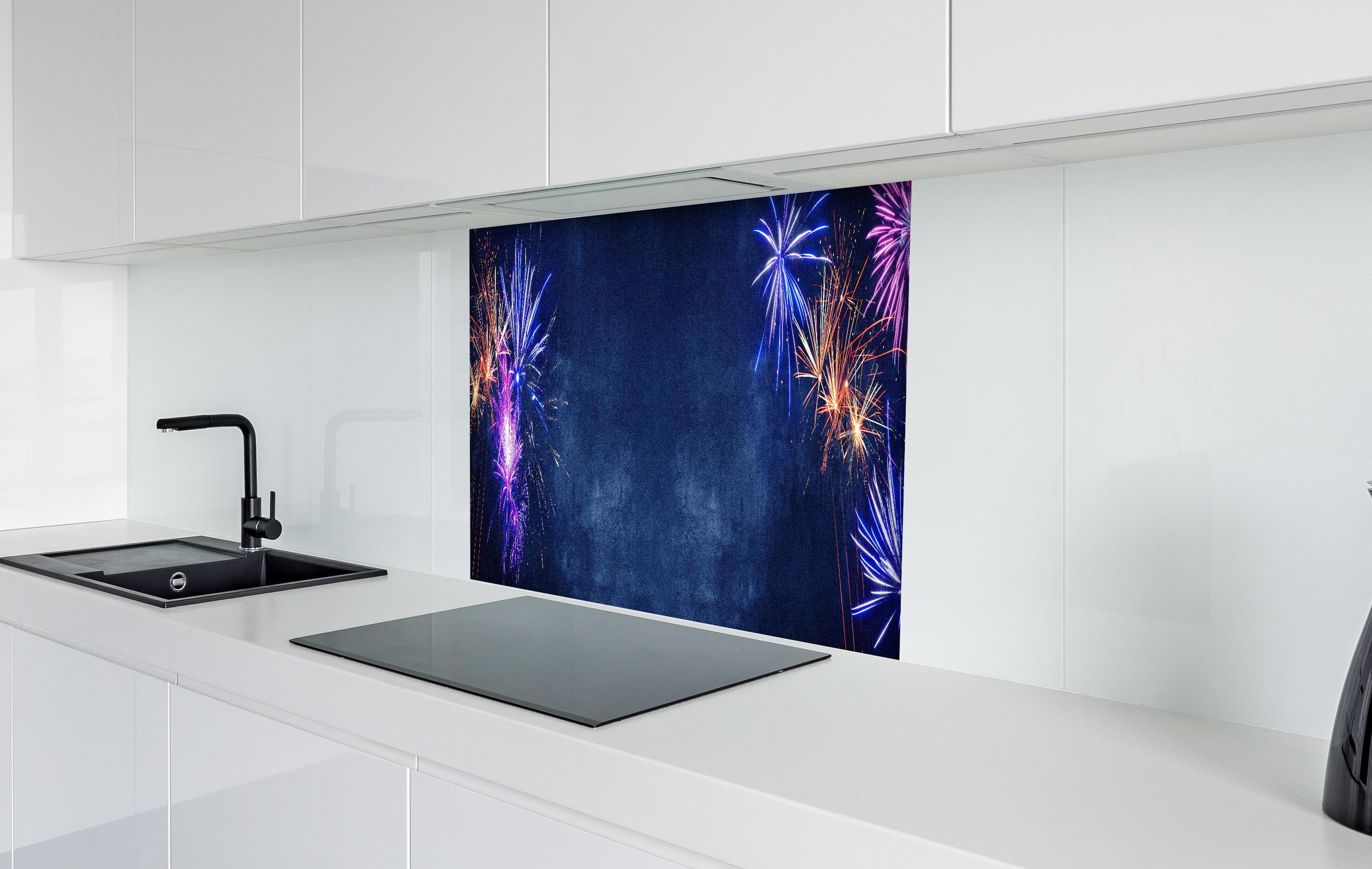 Spritzschutz - Buntes Silvester-Feuerwerk am Dunkelblauen Himmel hinter einem Cerankochfeld zwischen Holz-Kochutensilien
