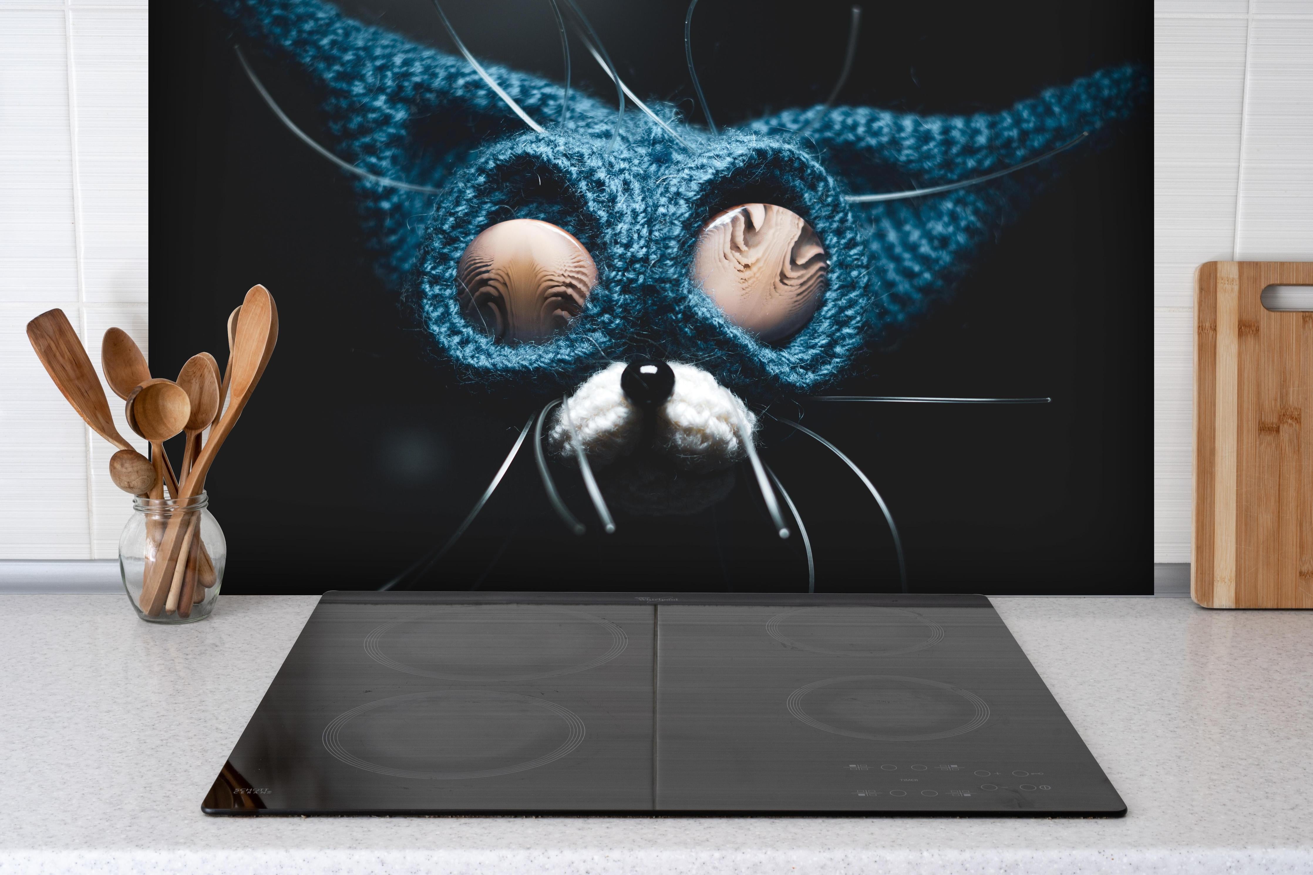 Spritzschutz - Cartoon Darstellung hinter einem Cerankochfeld zwischen Holz-Kochutensilien
