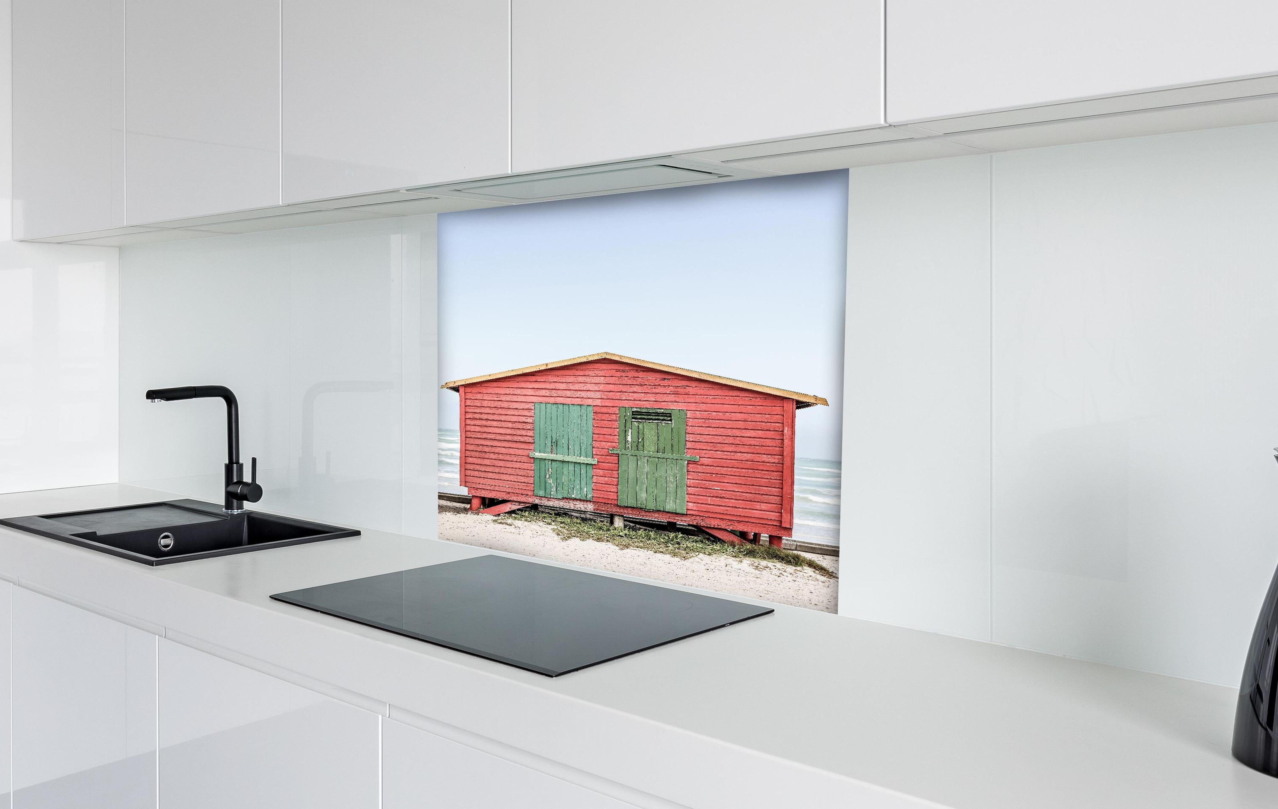 Spritzschutz - Charmante rote Strandhütte Küstenblick hinter einem Cerankochfeld zwischen Holz-Kochutensilien
