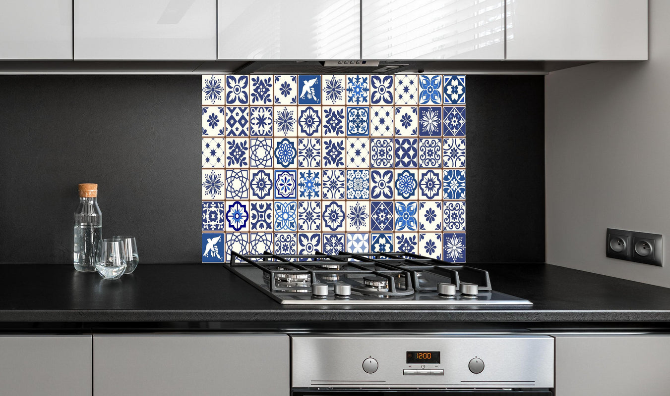 Spritzschutz - Dekorative blaue Keramik Kacheln mit Mustern hinter einem Cerankochfeld zwischen Holz-Kochutensilien
