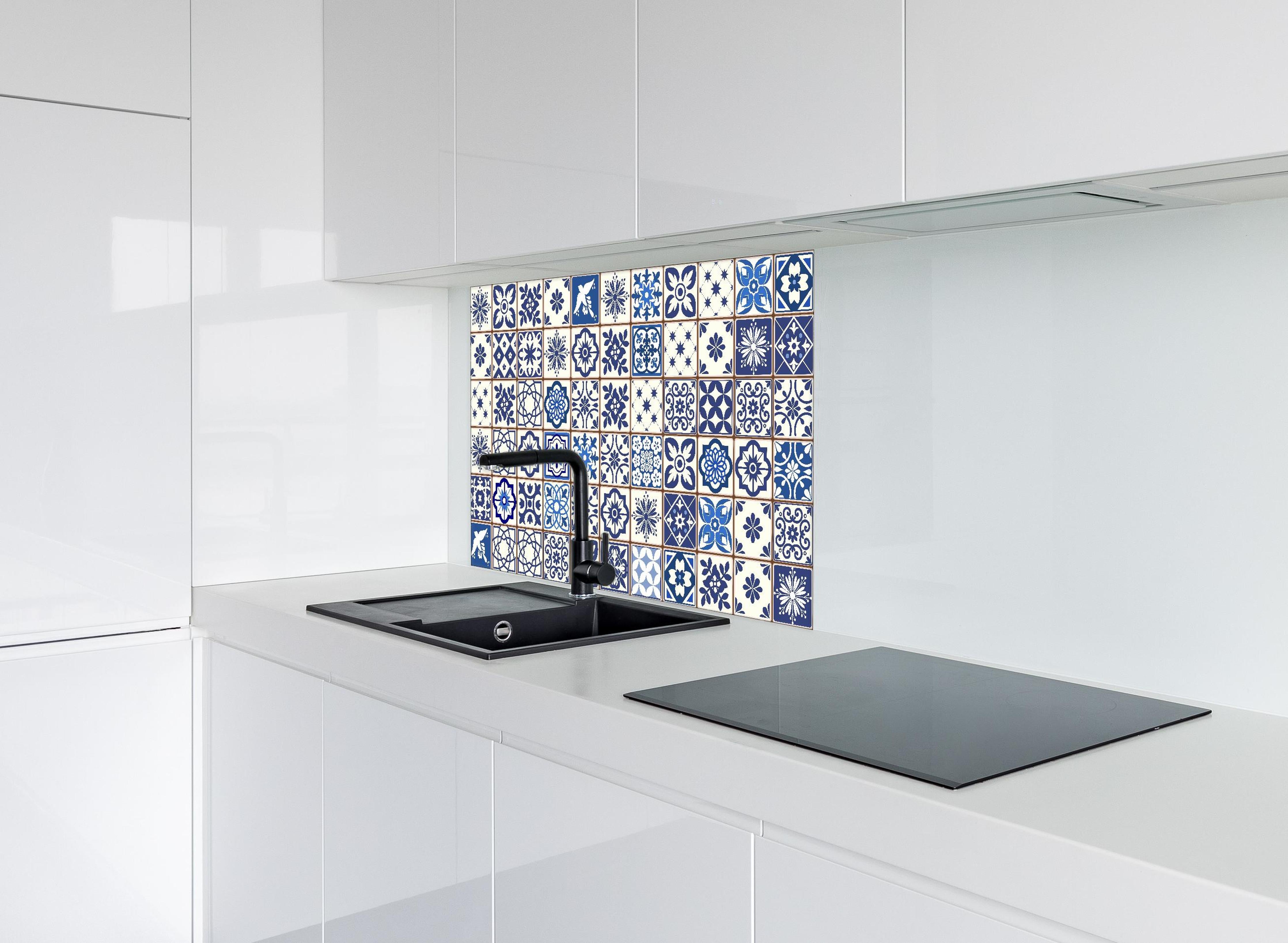 Spritzschutz - Dekorative blaue Keramik Kacheln mit Mustern hinter einem Cerankochfeld zwischen Holz-Kochutensilien
