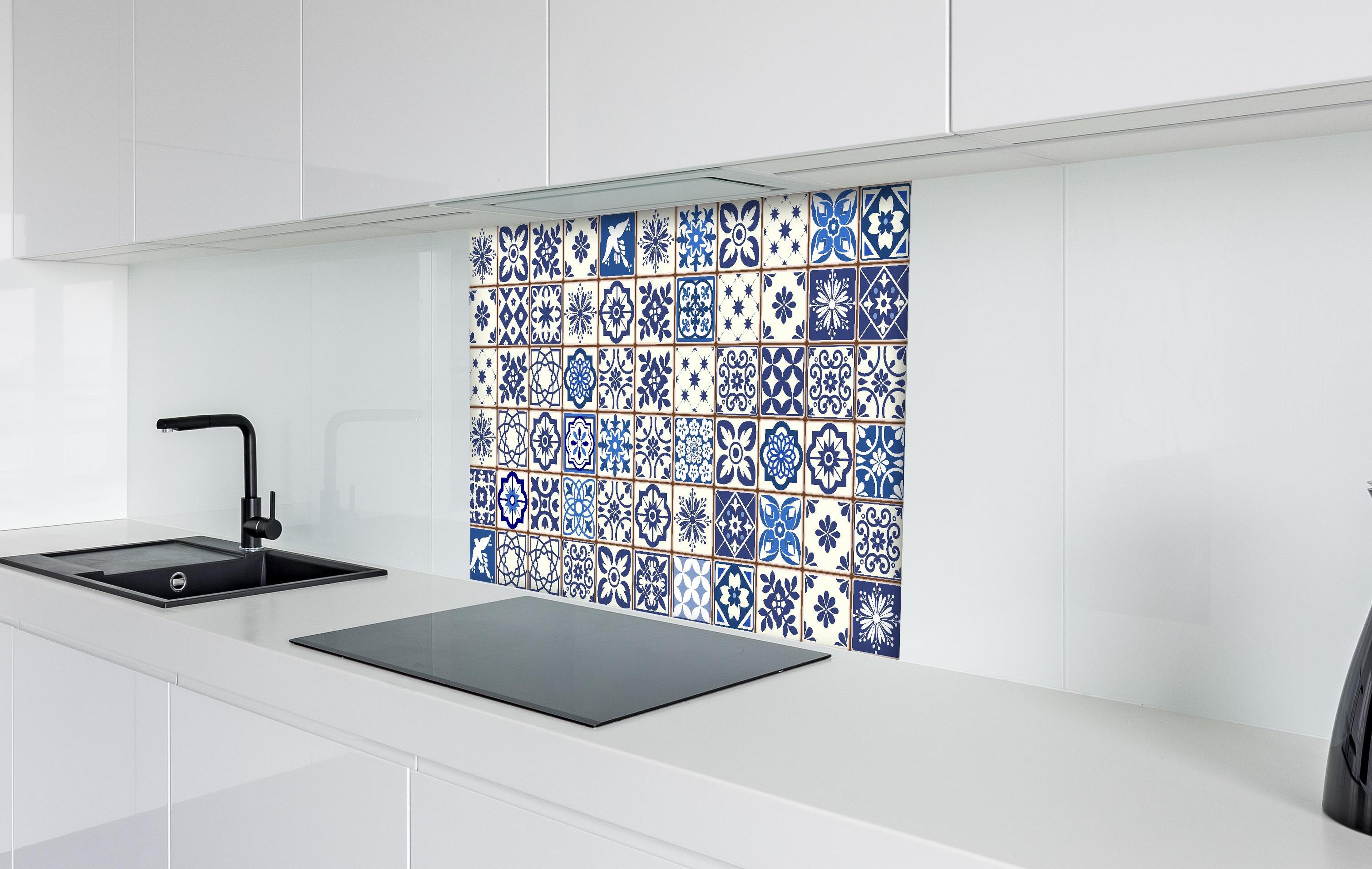 Spritzschutz - Dekorative blaue Keramik Kacheln mit Mustern hinter einem Cerankochfeld zwischen Holz-Kochutensilien
