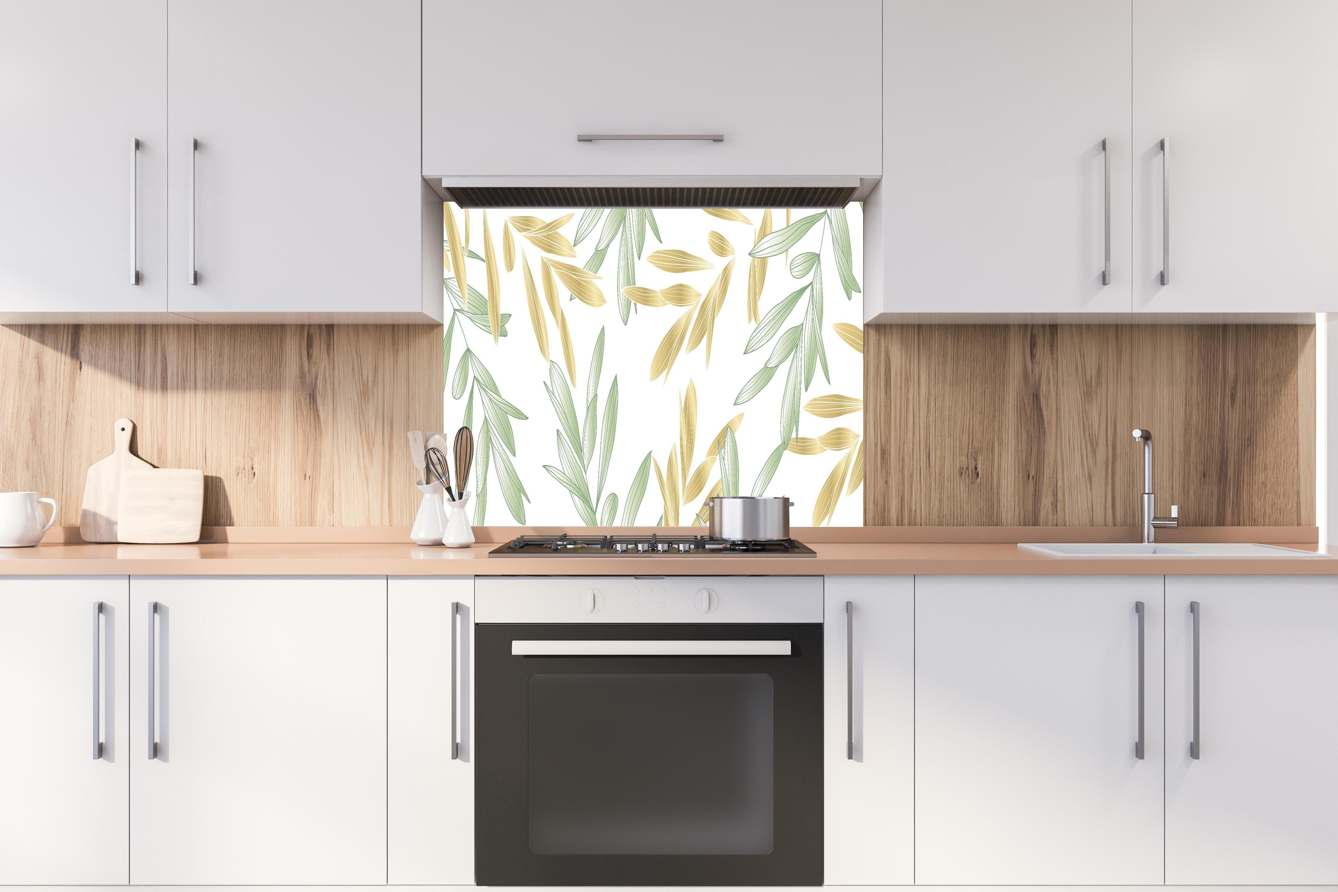 Spritzschutz - Dekoratives Grün-Gold Pflanzen-Design hinter einem Cerankochfeld zwischen Holz-Kochutensilien
