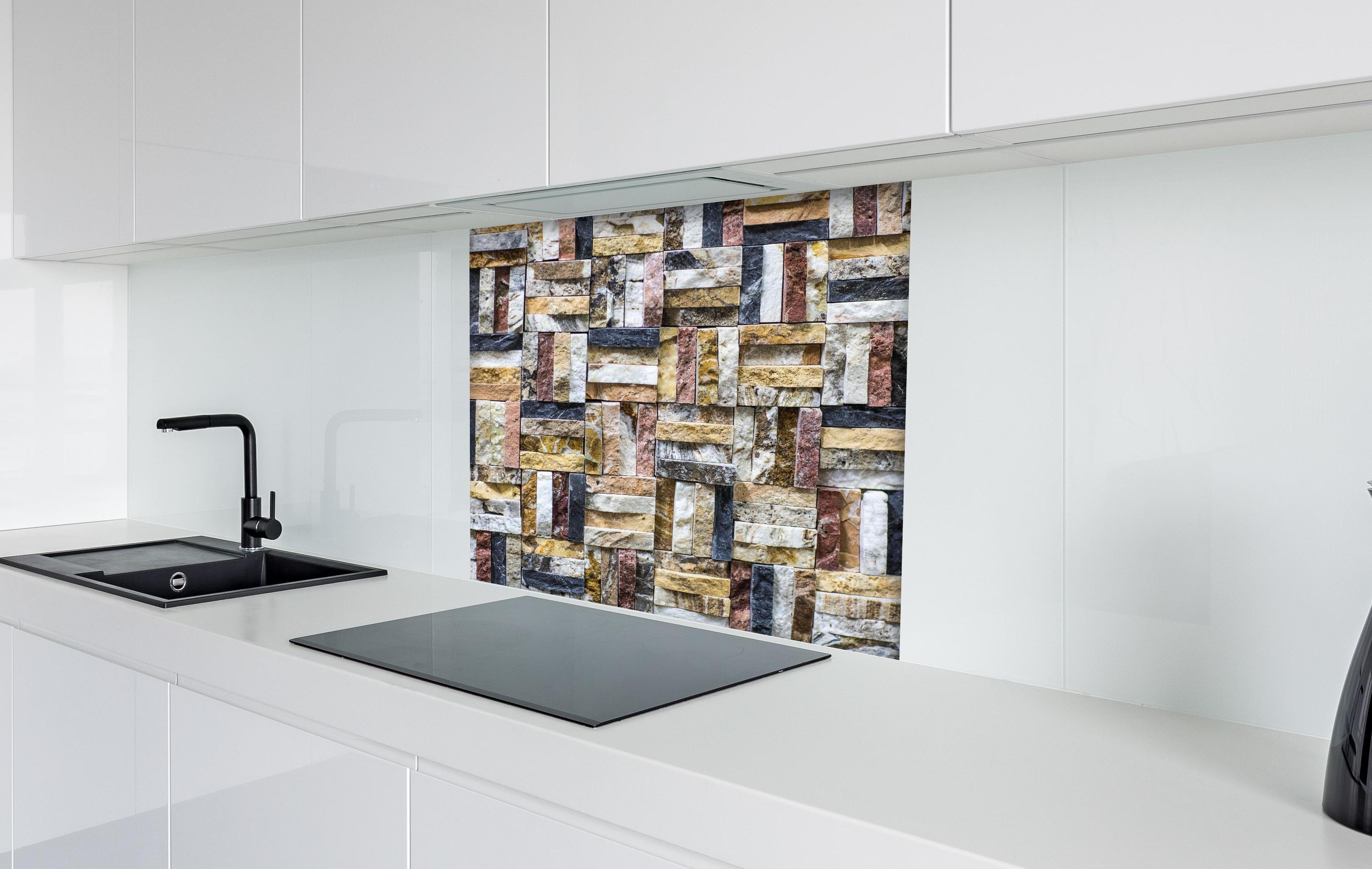 Spritzschutz - Dekoratives Wand Mosaik aus Naturstein hinter einem Cerankochfeld zwischen Holz-Kochutensilien
