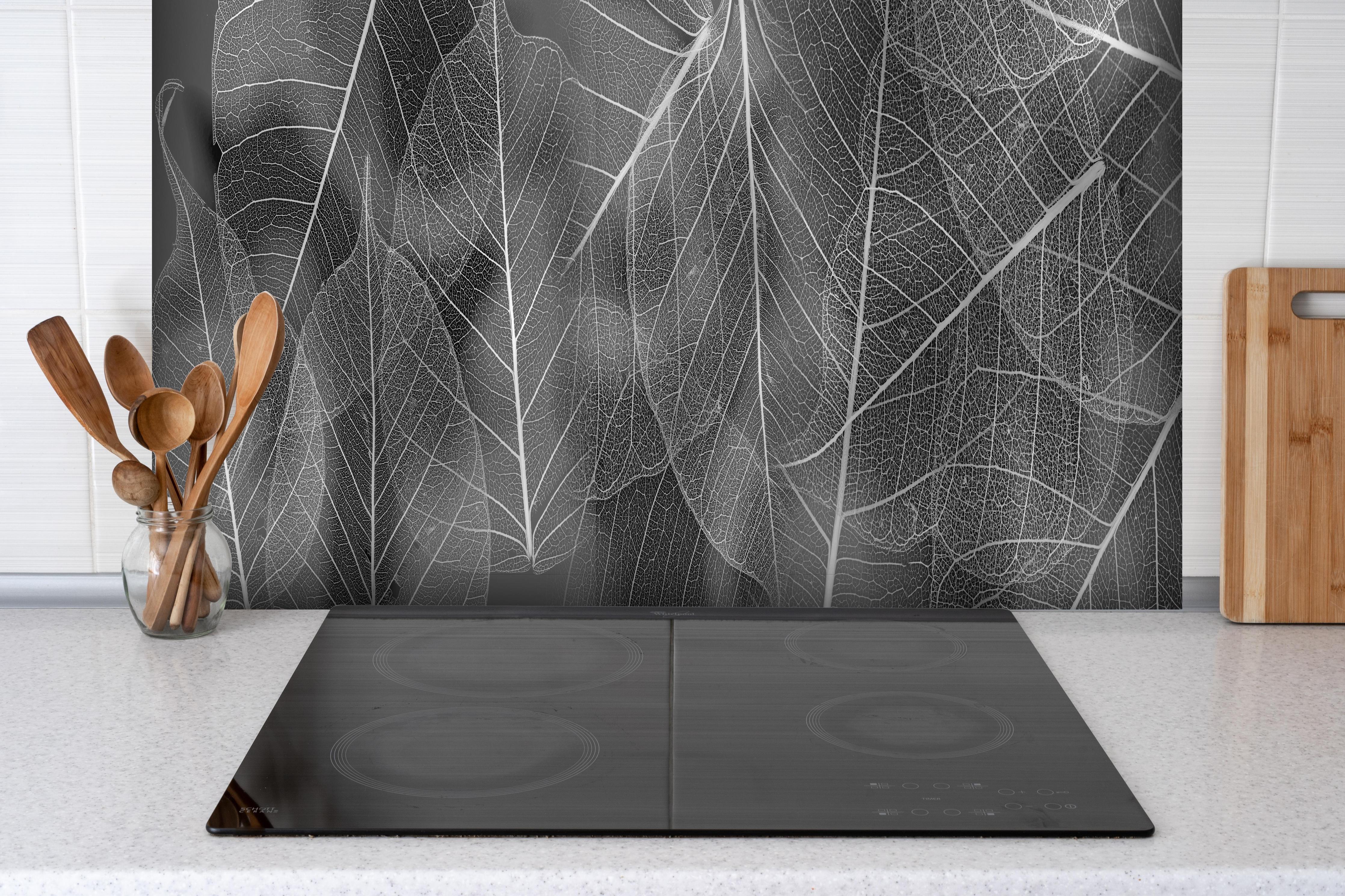 Spritzschutz - Detailreiche Grau-Weiße Blattstruktur Makro hinter einem Cerankochfeld zwischen Holz-Kochutensilien
