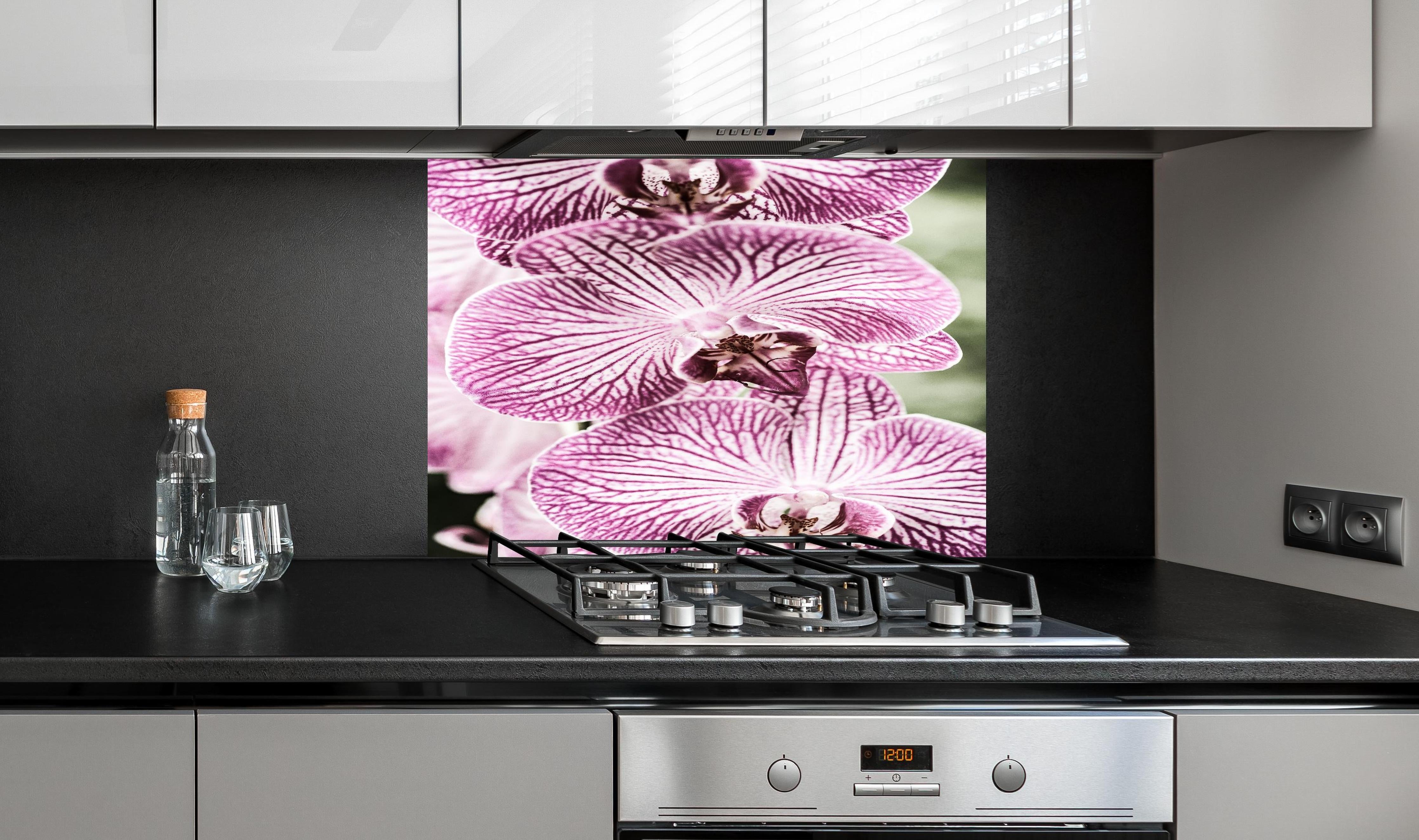 Spritzschutz - Detailreiche Orchideen Makroaufnahme in Pink-Lila hinter einem Cerankochfeld zwischen Holz-Kochutensilien
