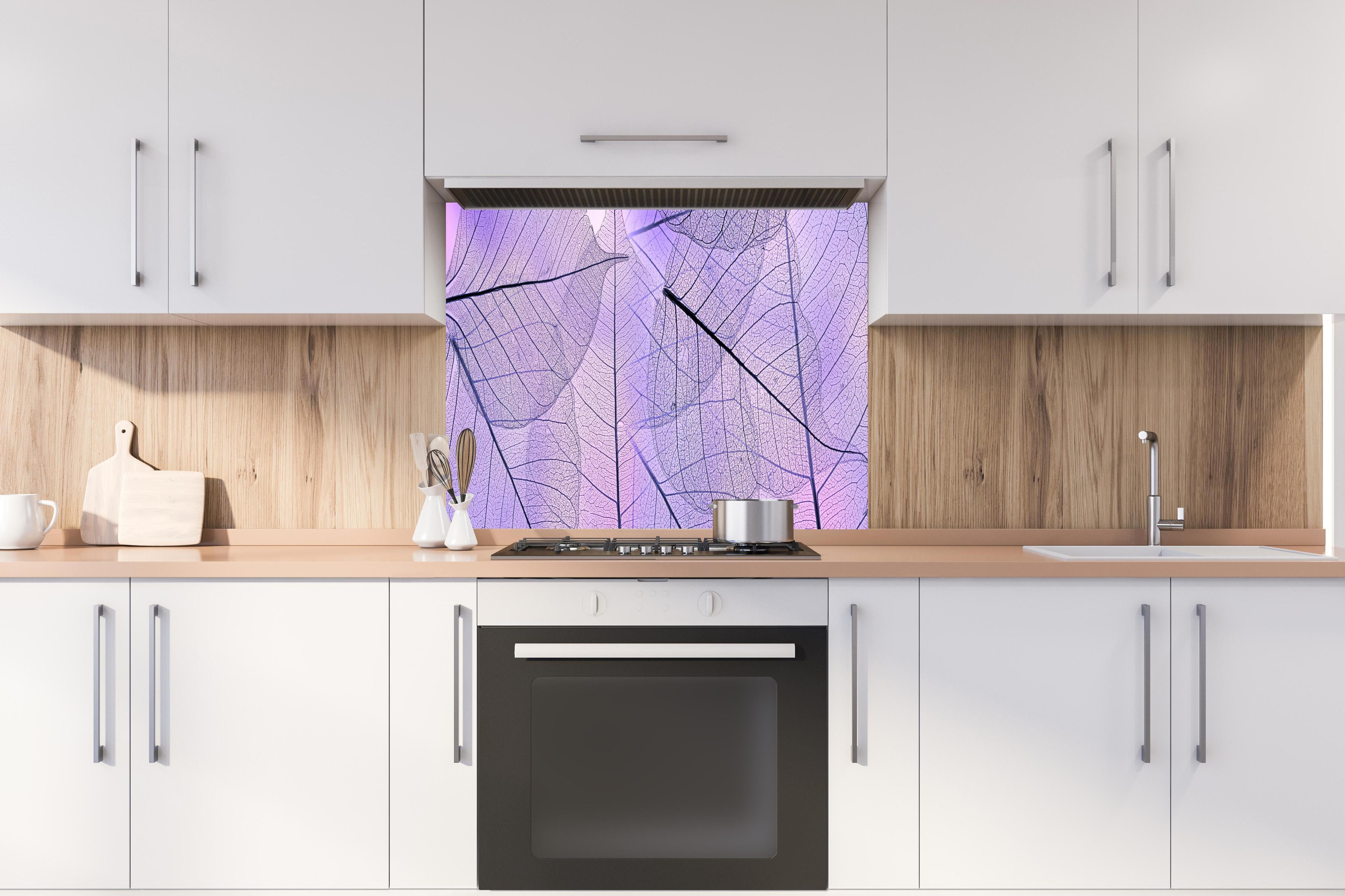 Spritzschutz - Detailreiche lila Blatt-Textur Nahaufnahme hinter einem Cerankochfeld zwischen Holz-Kochutensilien
