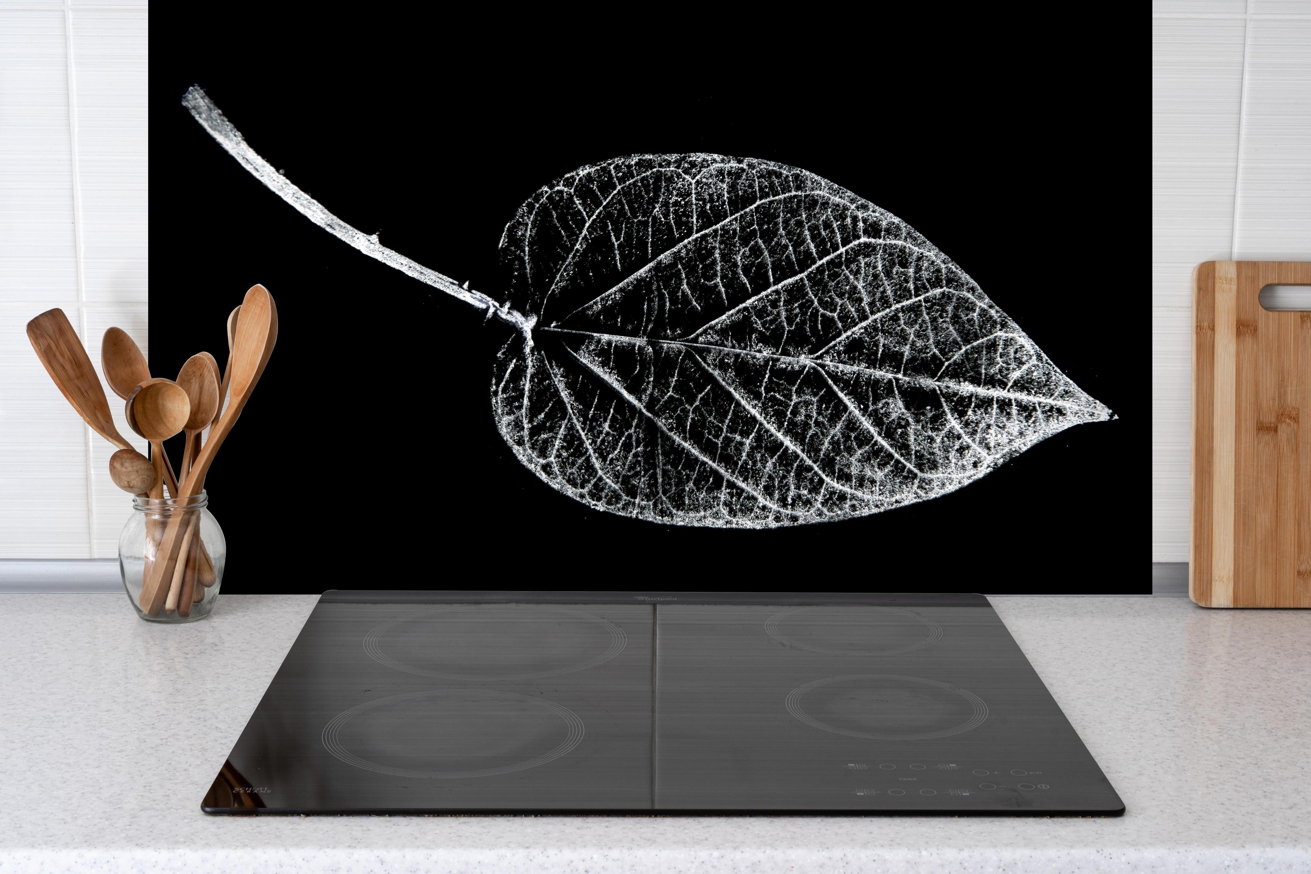 Spritzschutz - Detailreiches Laubblatt in Schwarz und Weiß hinter einem Cerankochfeld zwischen Holz-Kochutensilien
