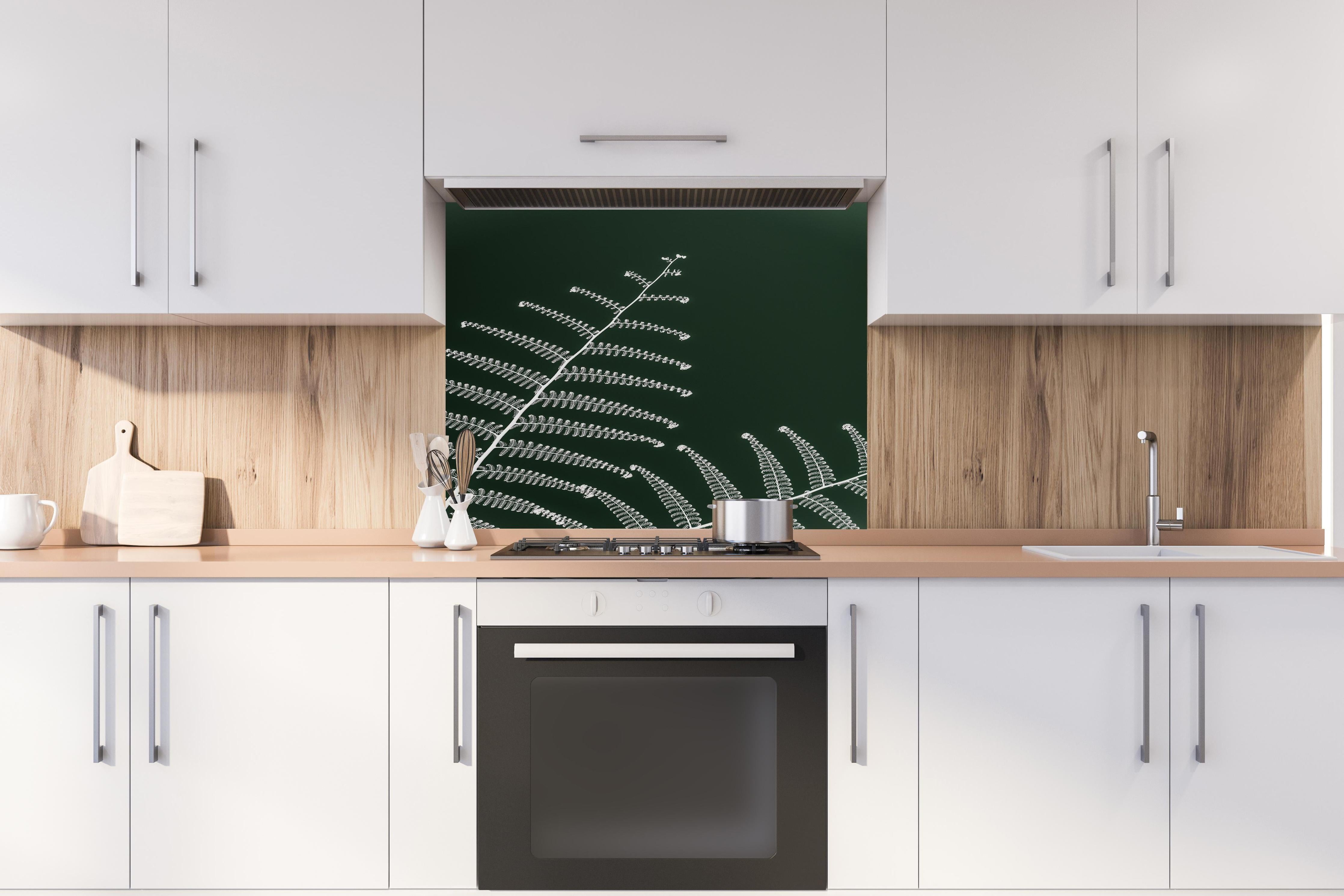Spritzschutz - Detailreiches, grünes Wald-Farn-Motiv hinter einem Cerankochfeld zwischen Holz-Kochutensilien
