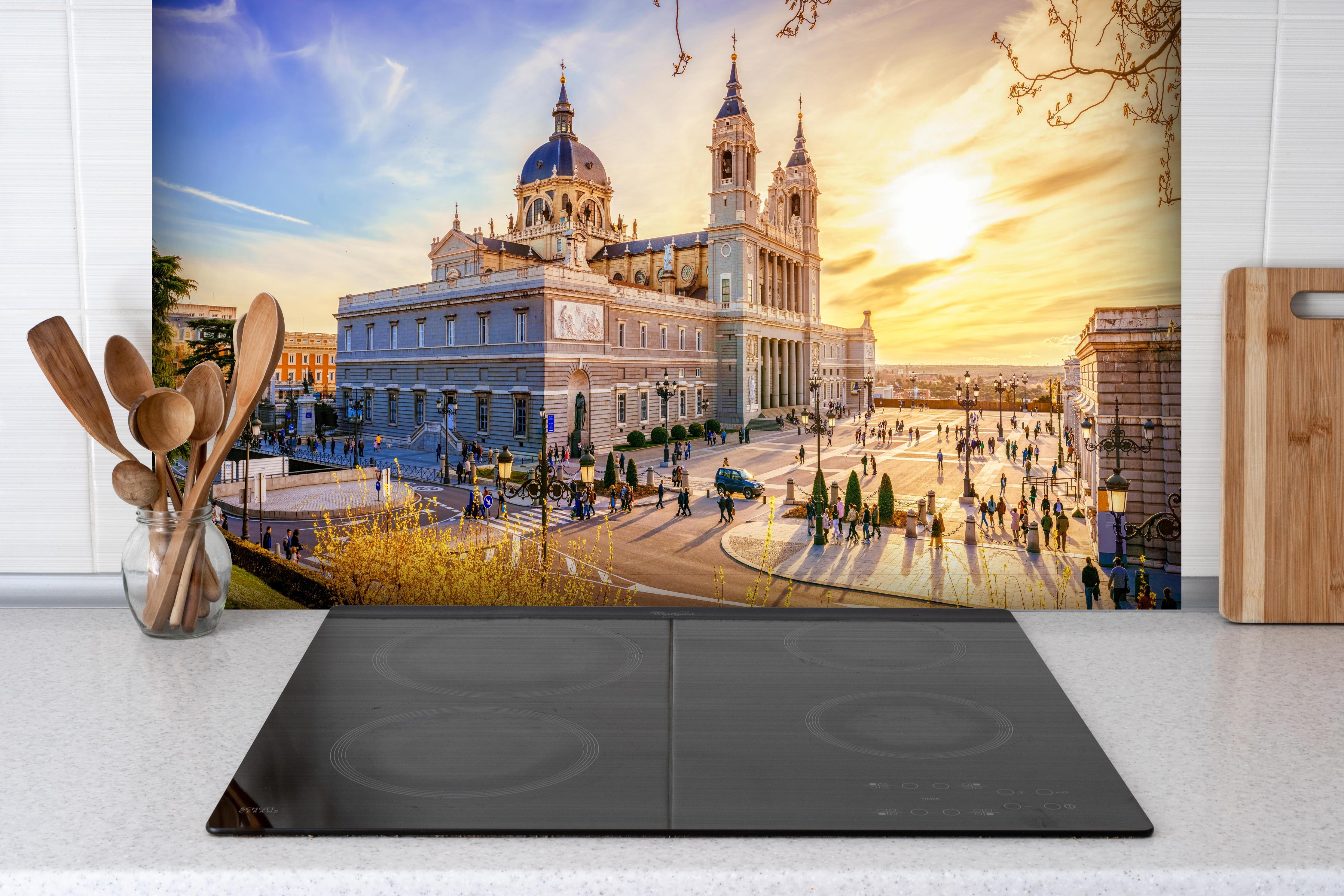 Spritzschutz - Die Kathedrale von Madrid hinter einem Cerankochfeld zwischen Holz-Kochutensilien
