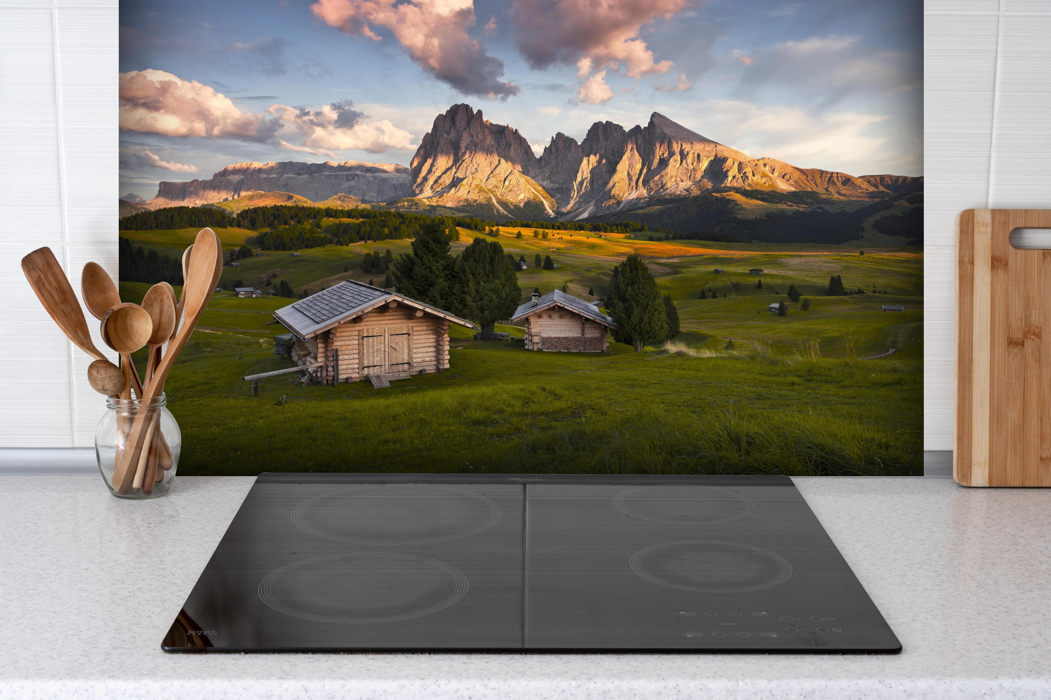 Spritzschutz - Dolomiten Alpenhütten bei Sonnenuntergang hinter einem Cerankochfeld zwischen Holz-Kochutensilien
