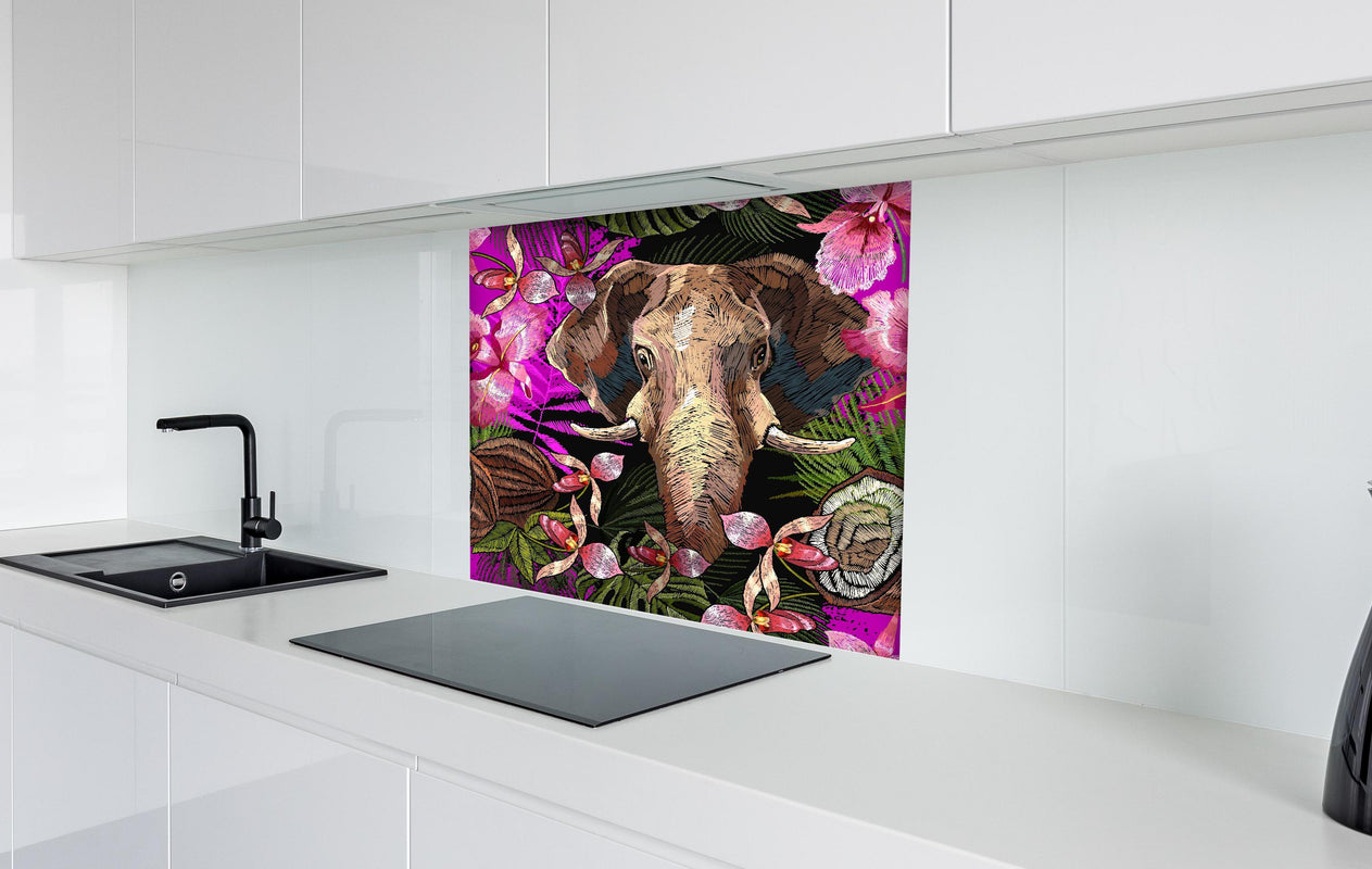 Spritzschutz - Dschungelnacht Elefant und tropische Blumen hinter einem Cerankochfeld zwischen Holz-Kochutensilien
