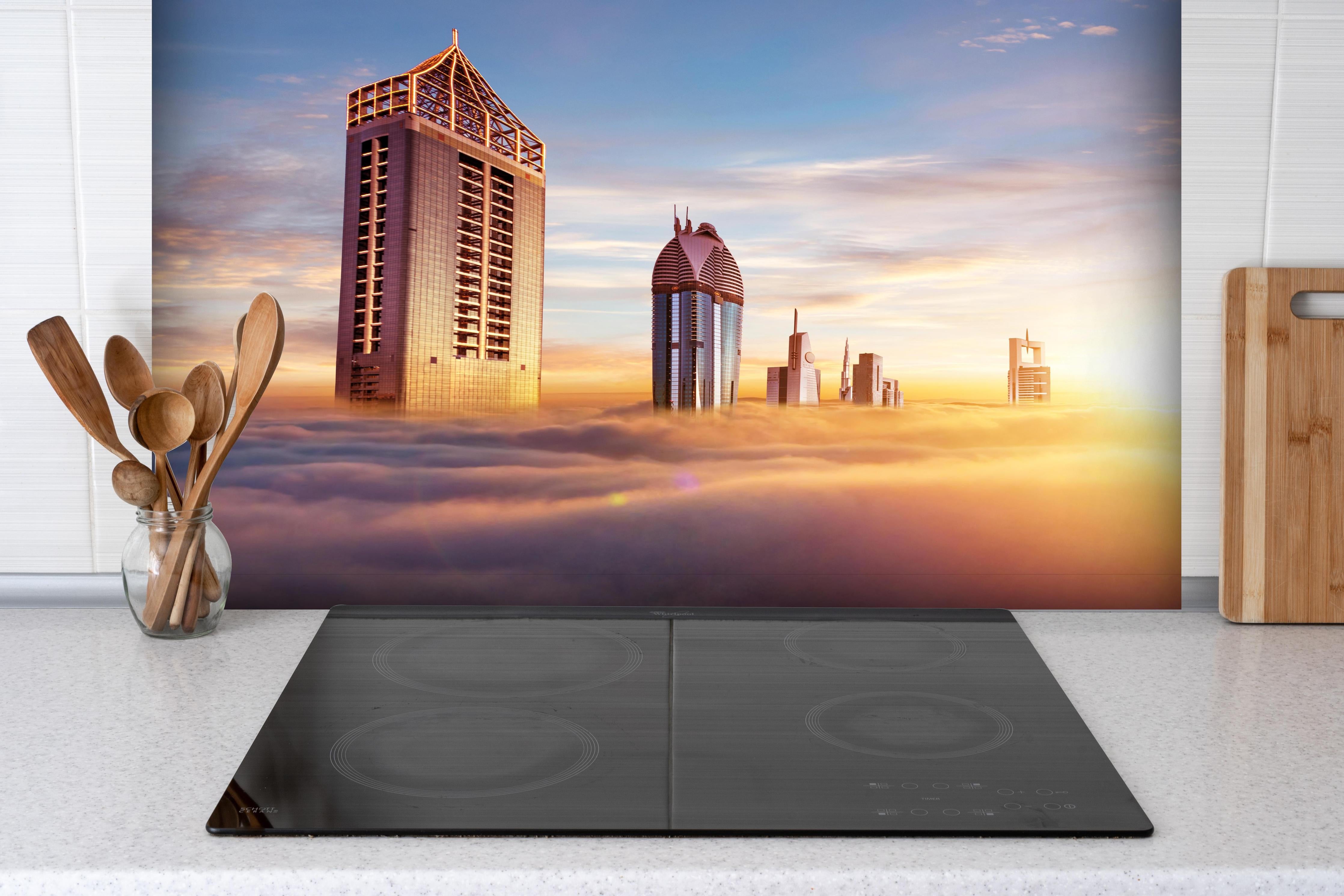 Spritzschutz - Dubai Wolkenkratzer über den Wolken bei Sonnenaufgang hinter einem Cerankochfeld zwischen Holz-Kochutensilien
