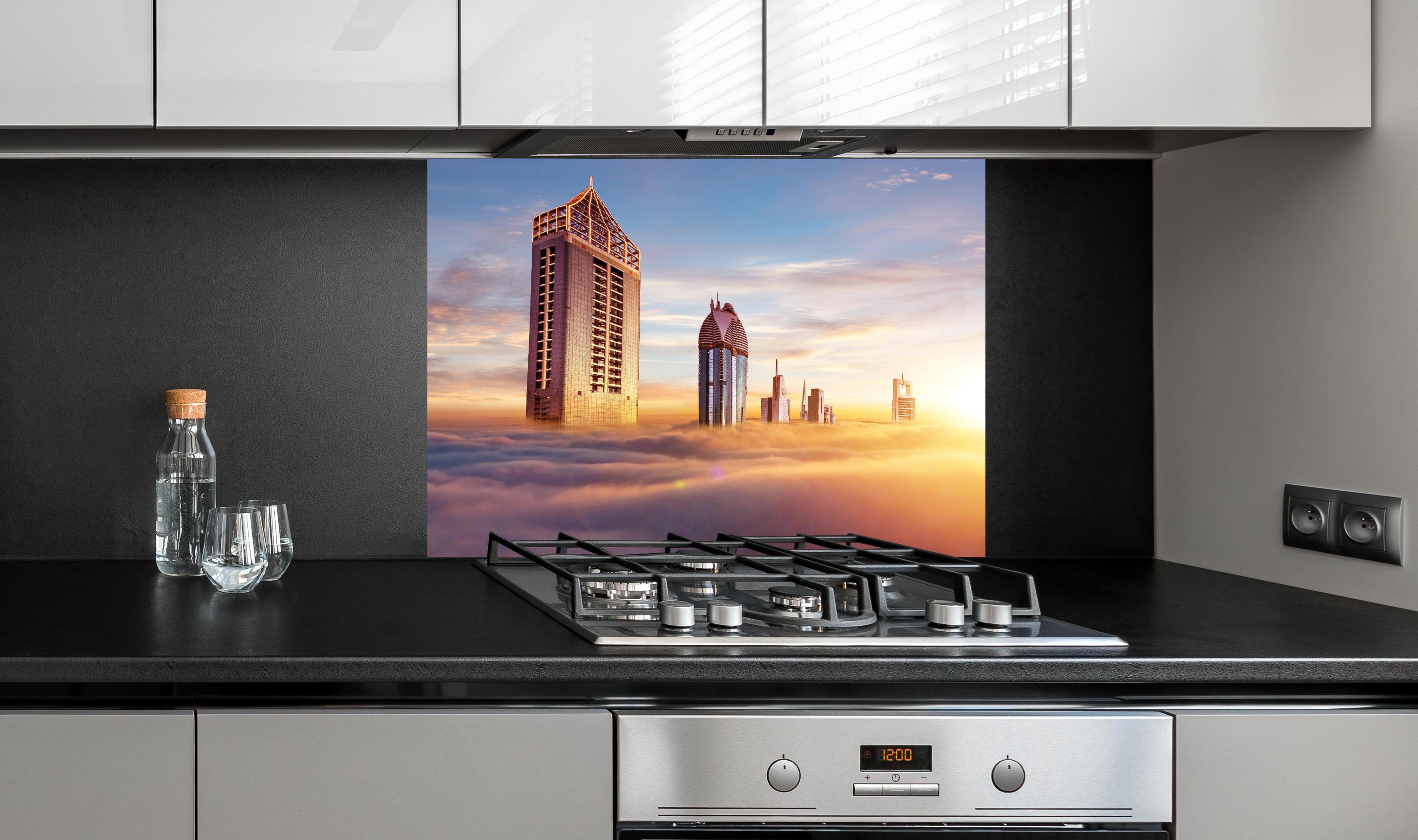 Spritzschutz - Dubai Wolkenkratzer über den Wolken bei Sonnenaufgang hinter einem Cerankochfeld zwischen Holz-Kochutensilien
