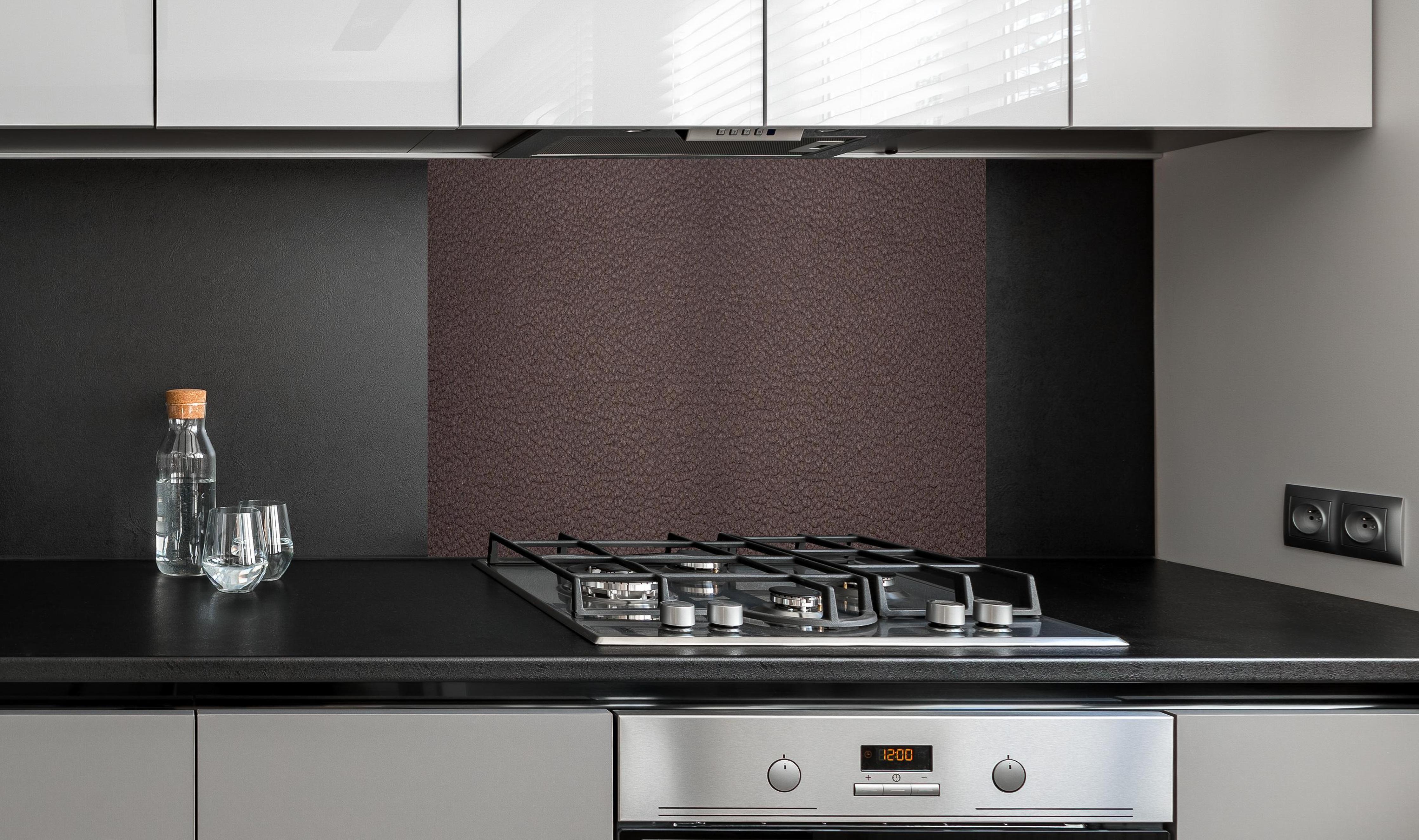 Spritzschutz - Dunkelbraune Lederstruktur im Panorama hinter einem Cerankochfeld zwischen Holz-Kochutensilien
