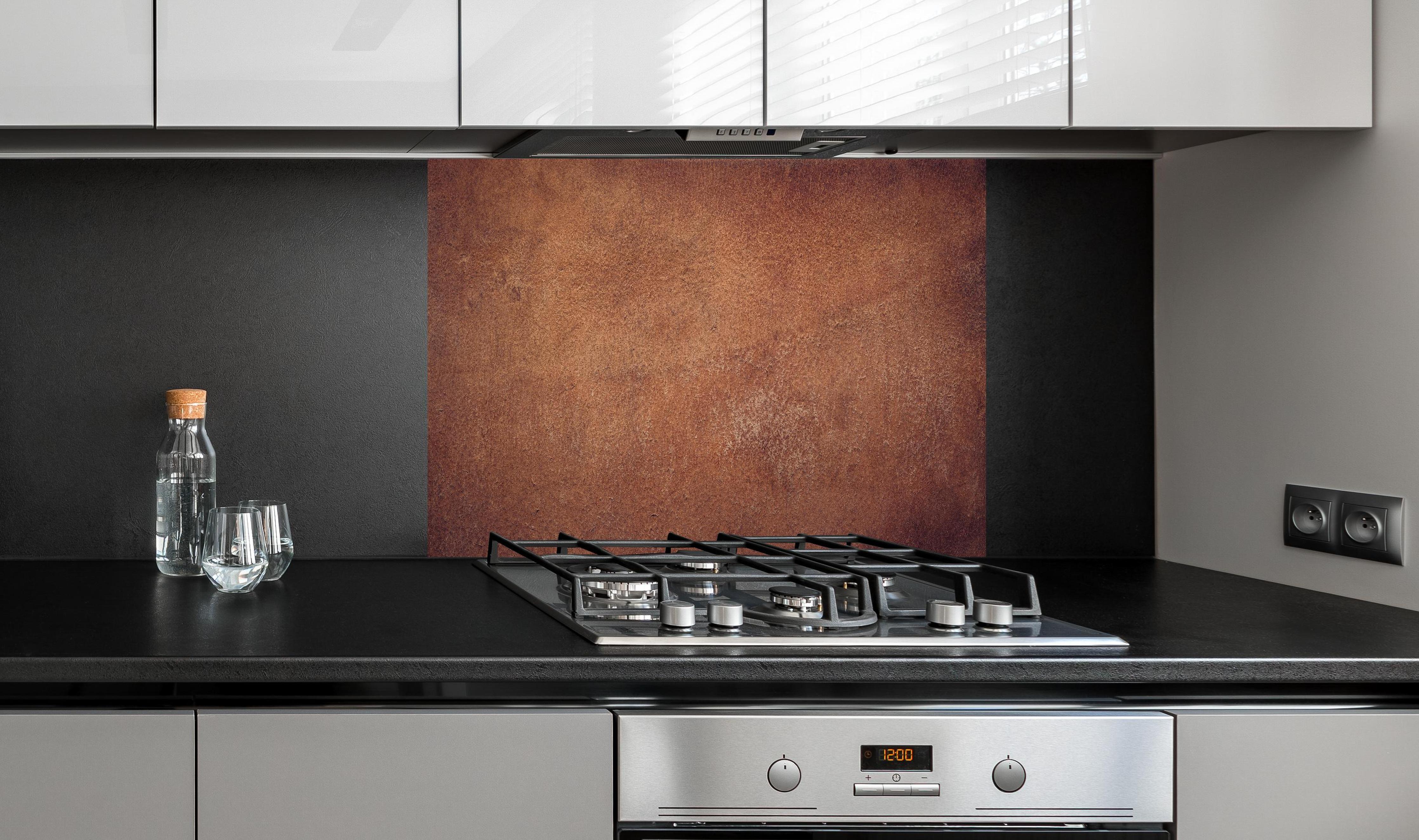 Spritzschutz - Dunkelbraune Ledertextur hinter einem Cerankochfeld zwischen Holz-Kochutensilien
