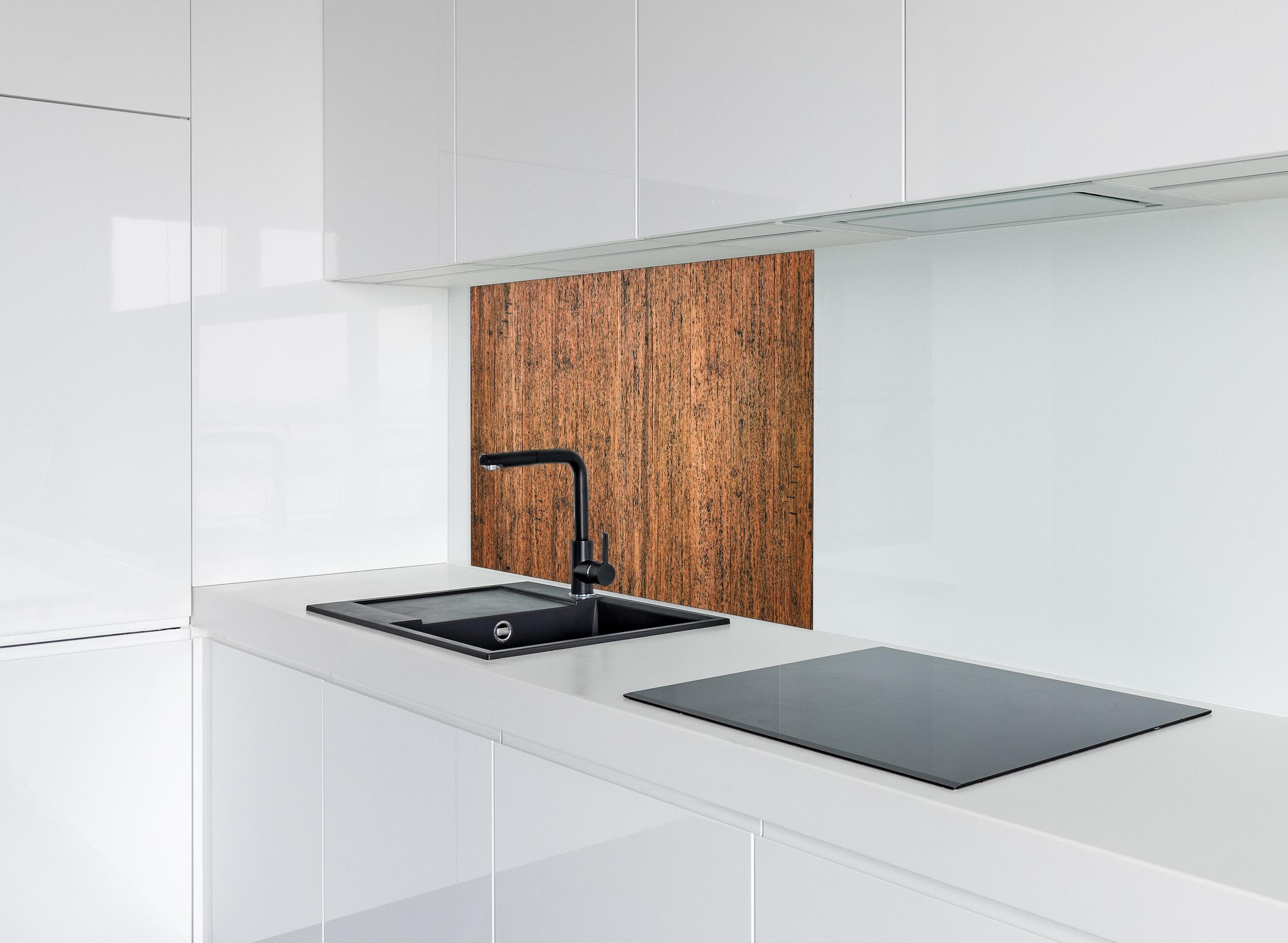 Spritzschutz - Dunkelbraunes rustikales Holzbrett hinter einem Cerankochfeld zwischen Holz-Kochutensilien
