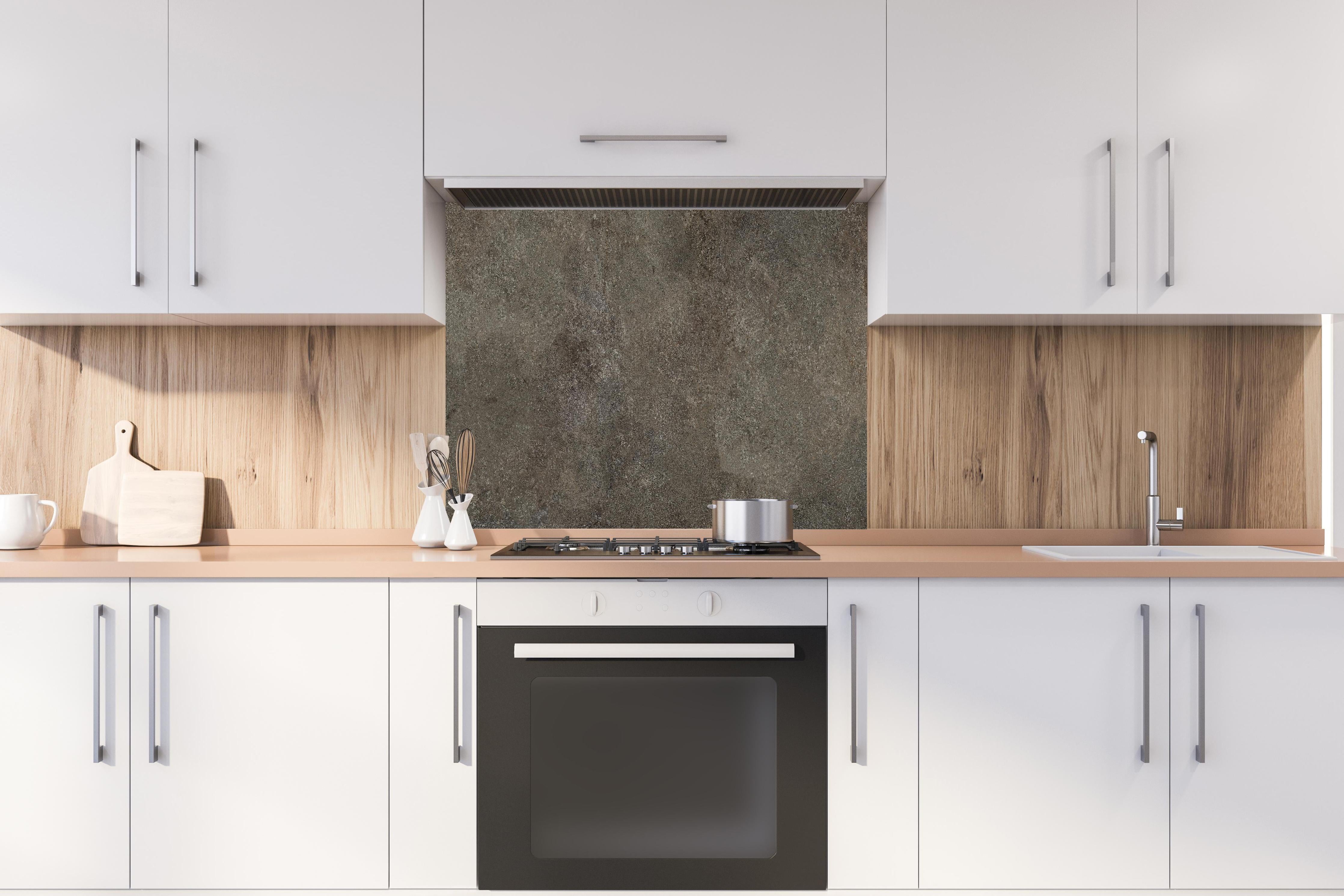 Spritzschutz - Dunkelgrauer schwarzer Schieferhintergrund hinter einem Cerankochfeld zwischen Holz-Kochutensilien
