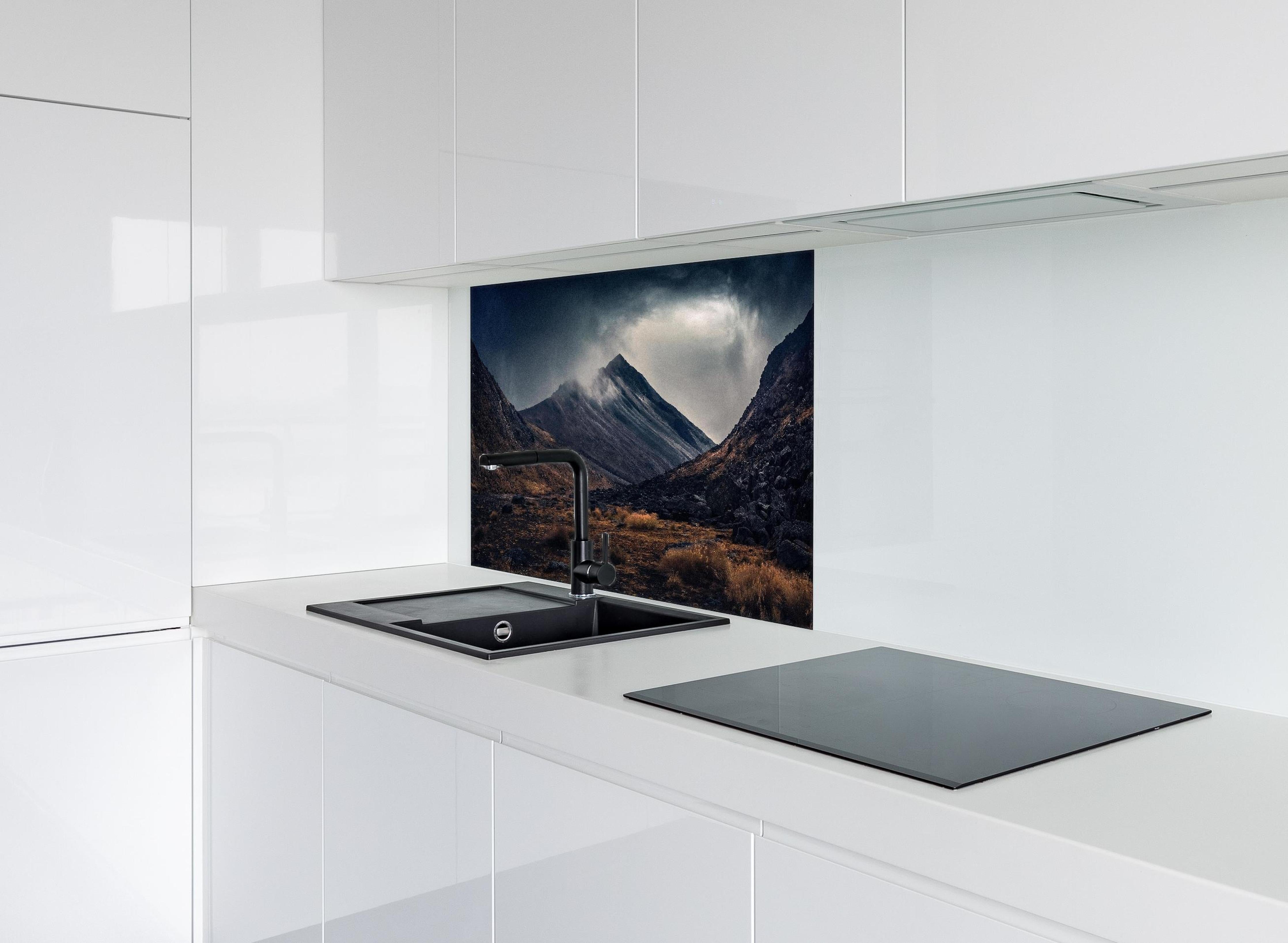 Spritzschutz - Dunkle Wolken Aufziehend über Bergspitze hinter einem Cerankochfeld zwischen Holz-Kochutensilien
