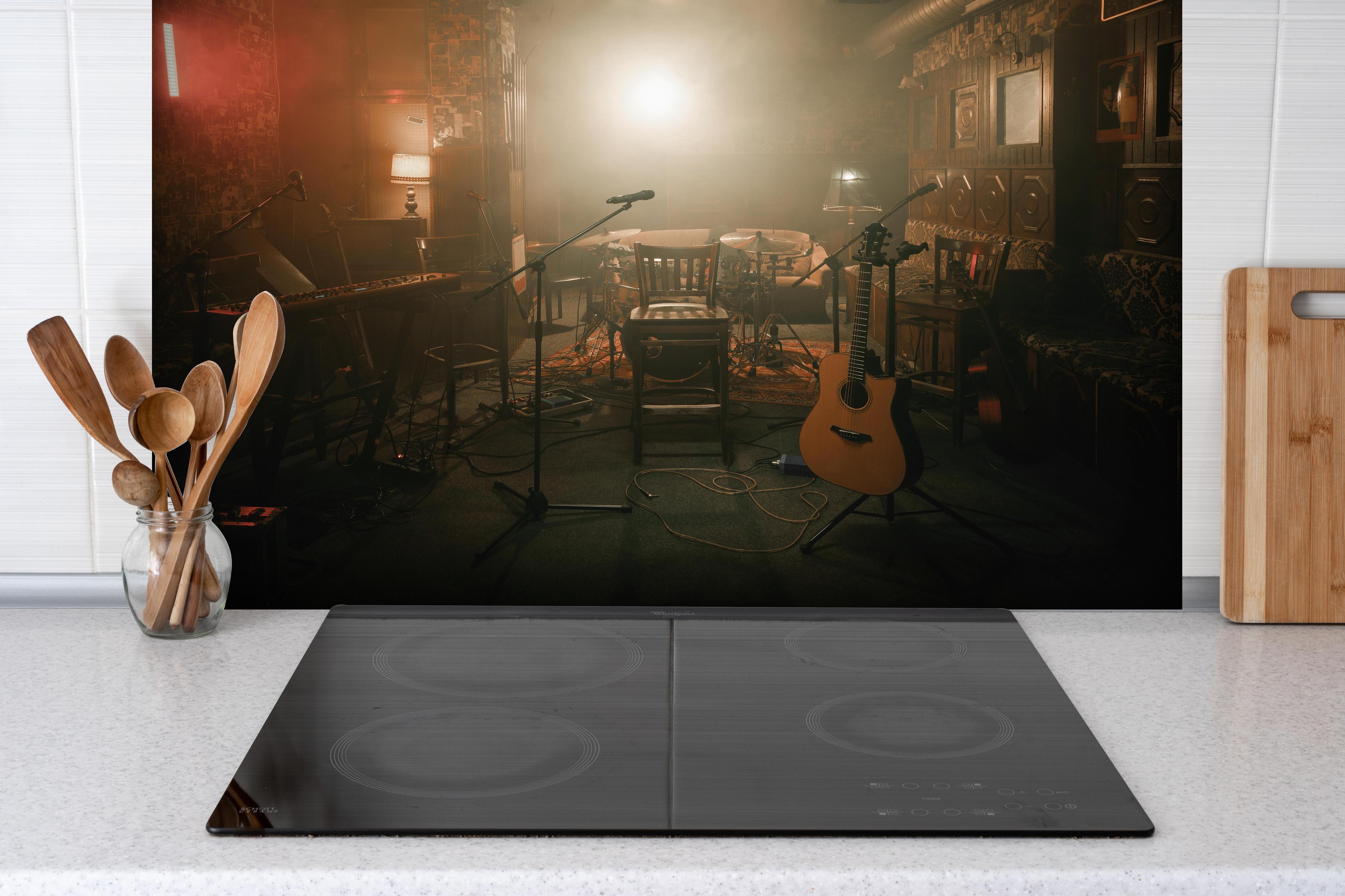 Spritzschutz - Dunkle leere Bühne hinter einem Cerankochfeld zwischen Holz-Kochutensilien
