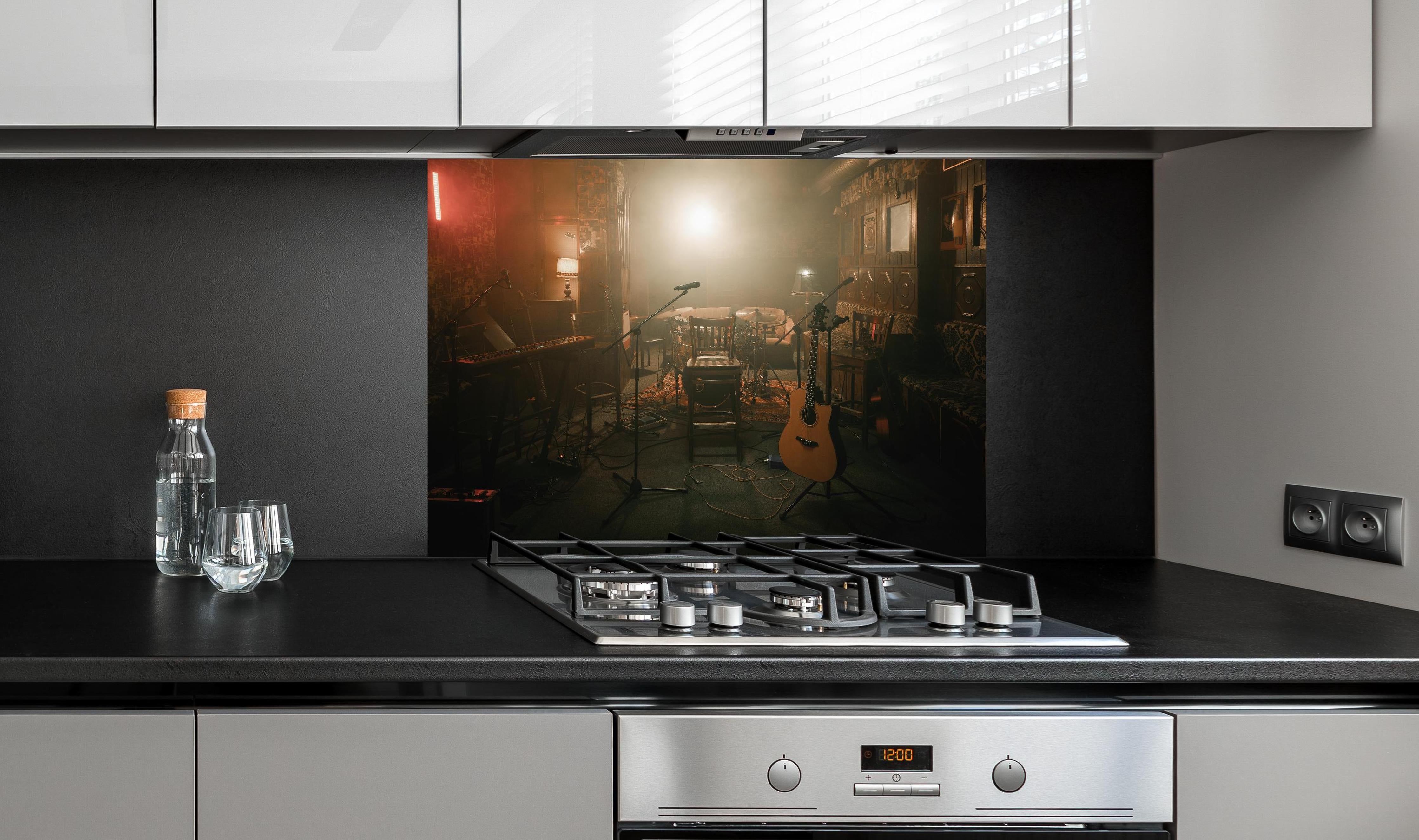 Spritzschutz - Dunkle leere Bühne hinter einem Cerankochfeld zwischen Holz-Kochutensilien
