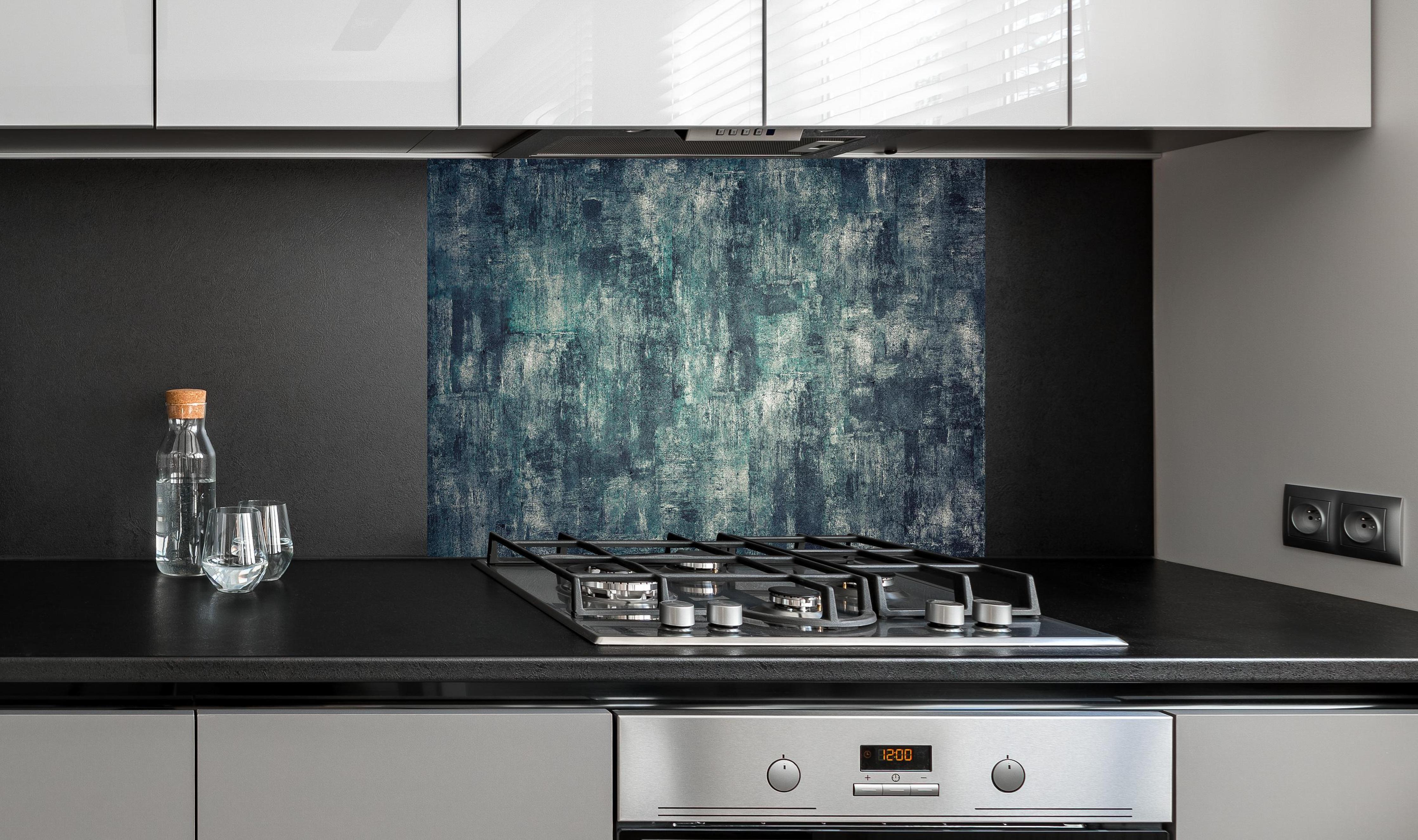 Spritzschutz - Dunkler Beton Panorama in Ölfarbton hinter einem Cerankochfeld zwischen Holz-Kochutensilien
