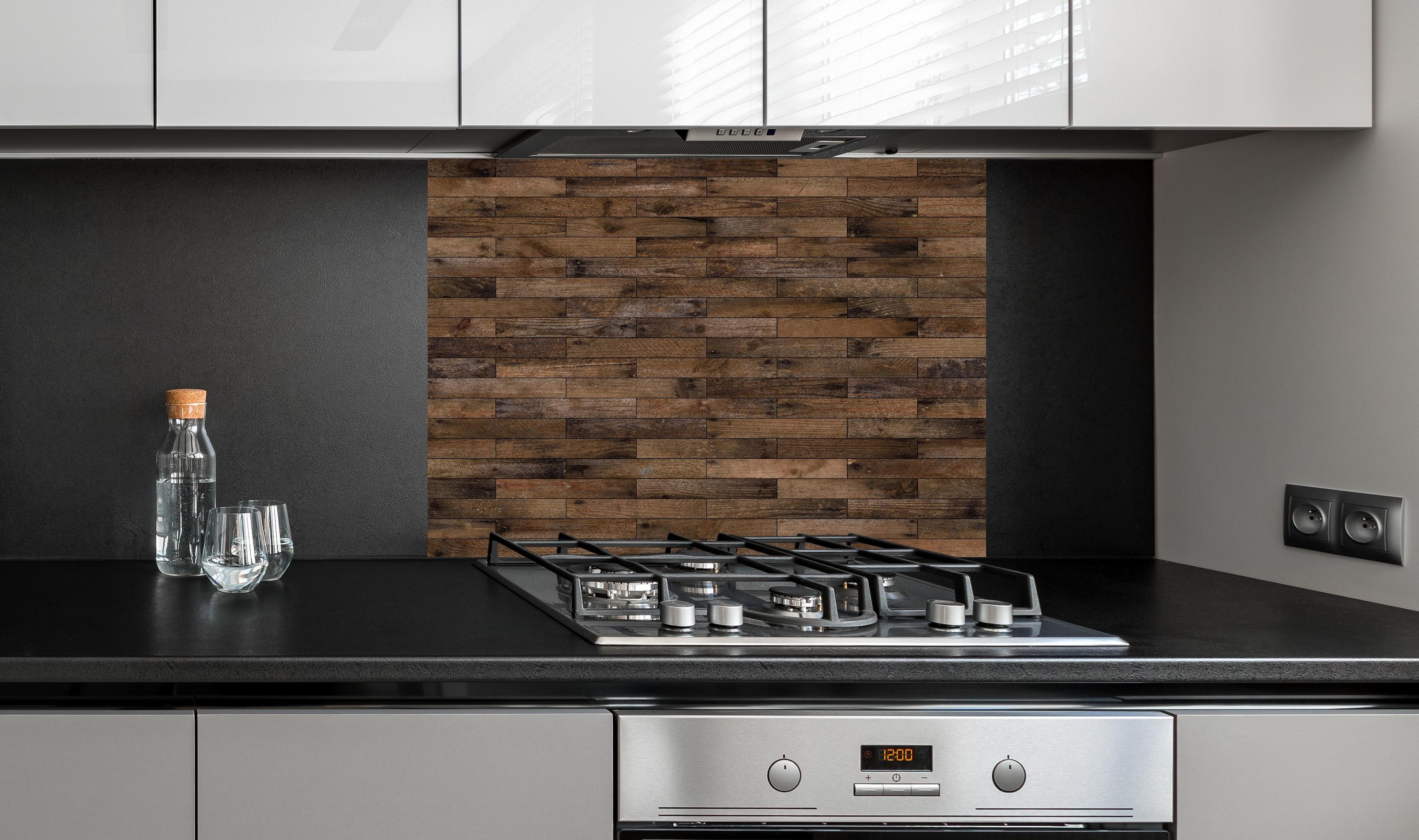 Spritzschutz - Dunkles Holzmuster hinter einem Cerankochfeld zwischen Holz-Kochutensilien
