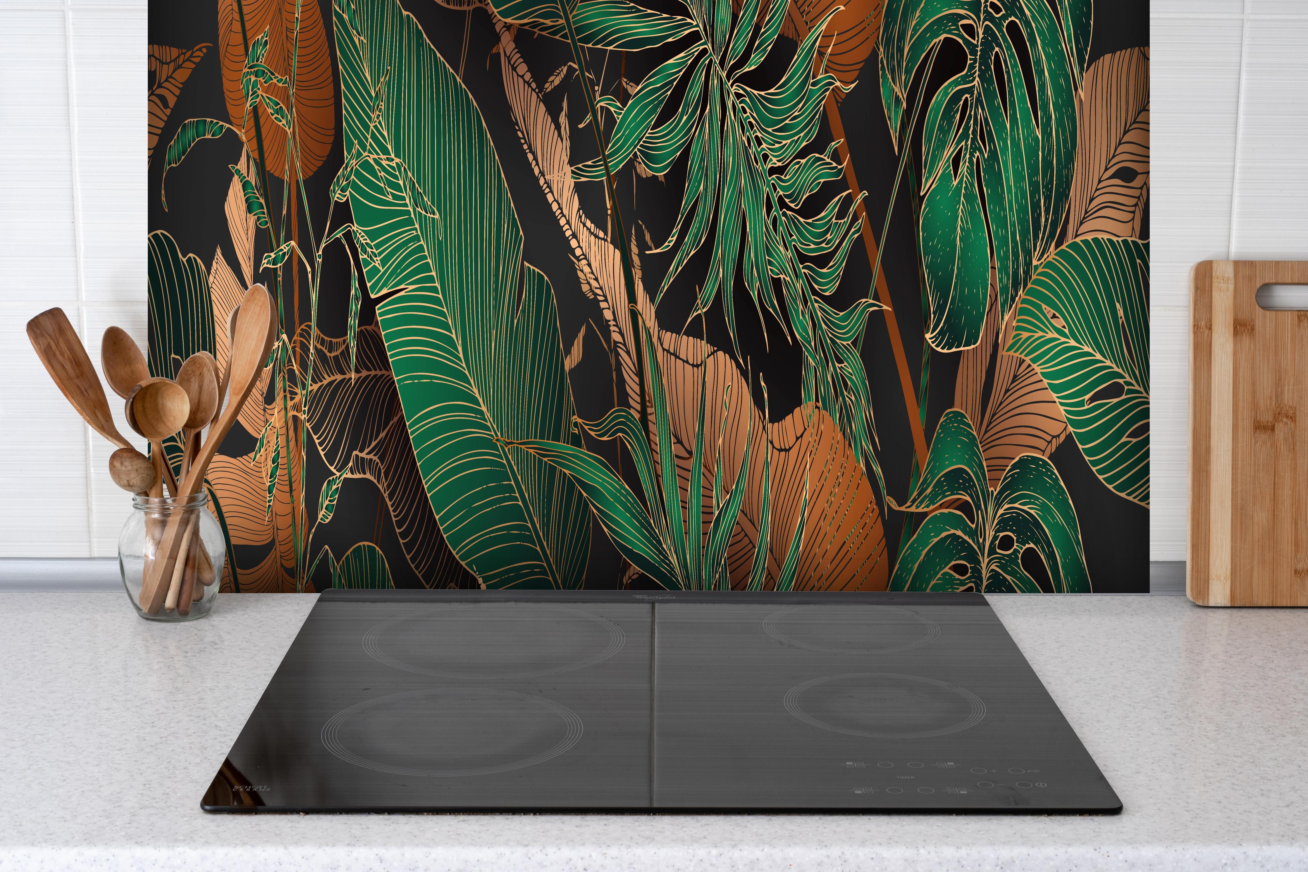 Spritzschutz - Dunkles Tropenblatt-Design Textil-Optik hinter einem Cerankochfeld zwischen Holz-Kochutensilien
